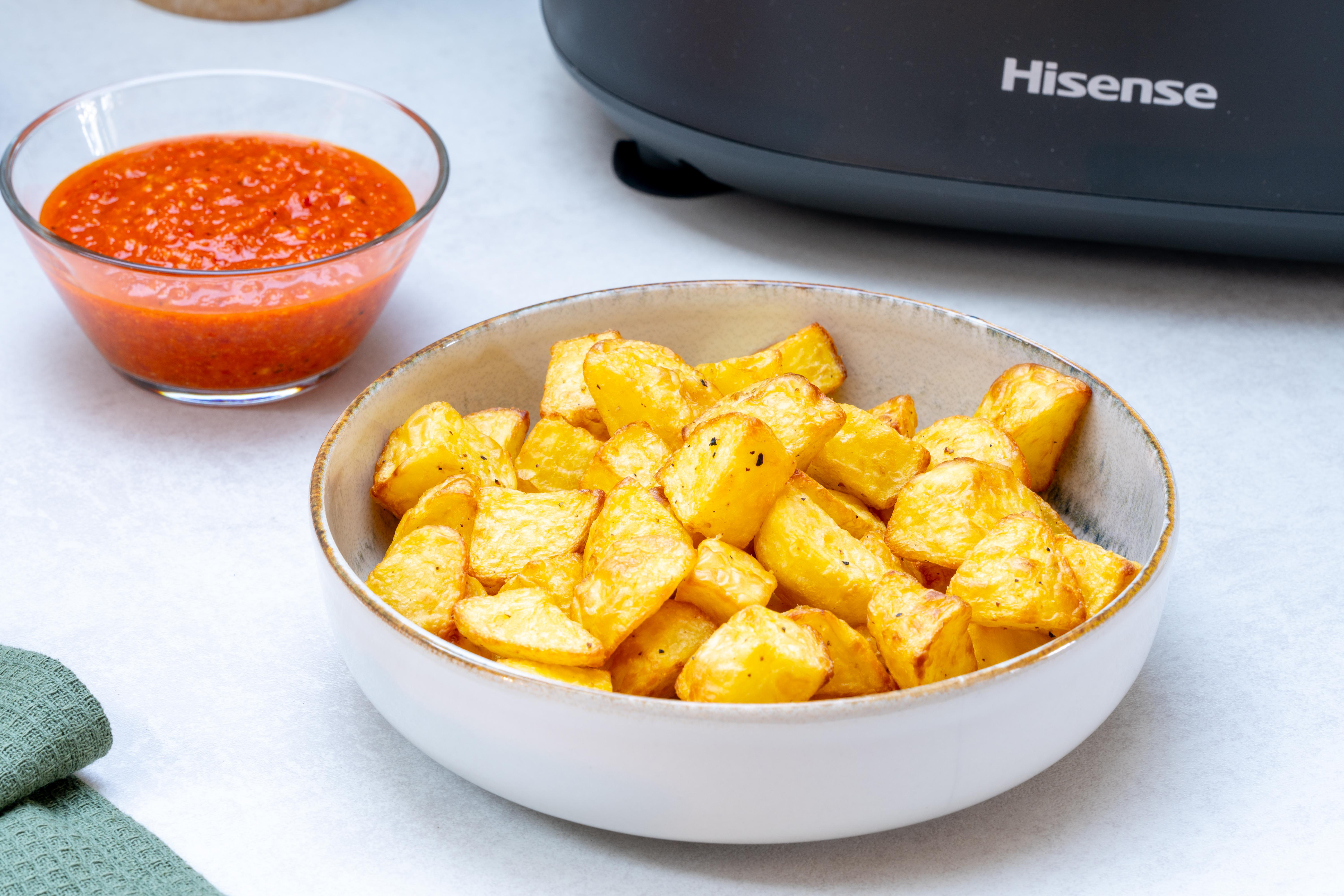 Schüssel mit Bratkartoffeln neben einer Schüssel mit roter Soße und einem schwarzen Hisense-Gerät.