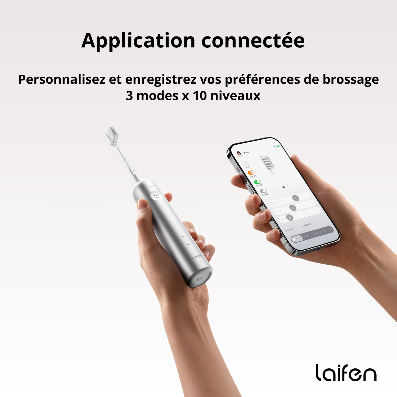 Personne tenant une brosse à dents électrique argentée, montrant l'écran du téléphone.