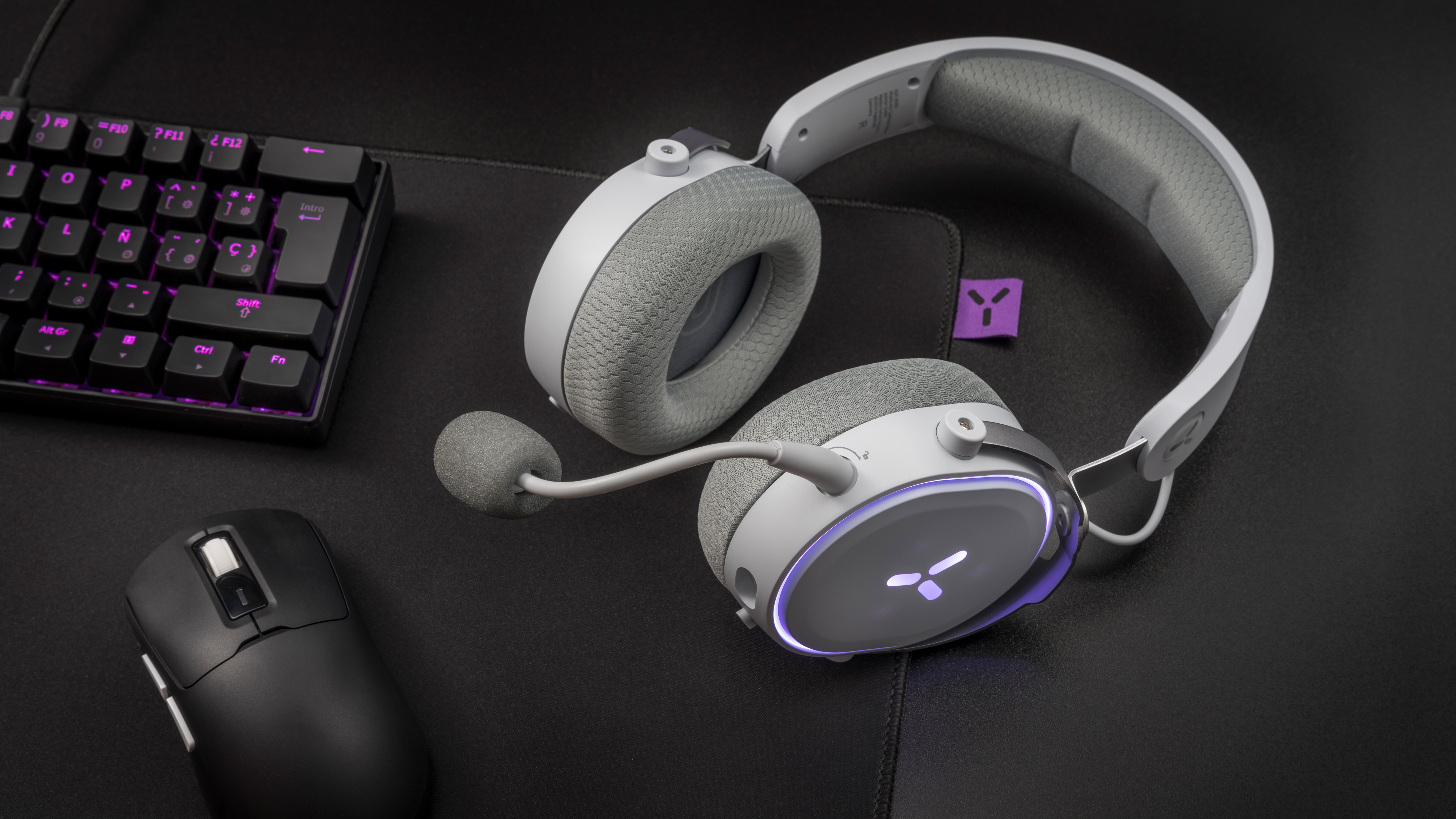 Zestaw słuchawkowy dla graczy z mikrofonem, klawiaturą i myszą na czarnej powierzchni.
