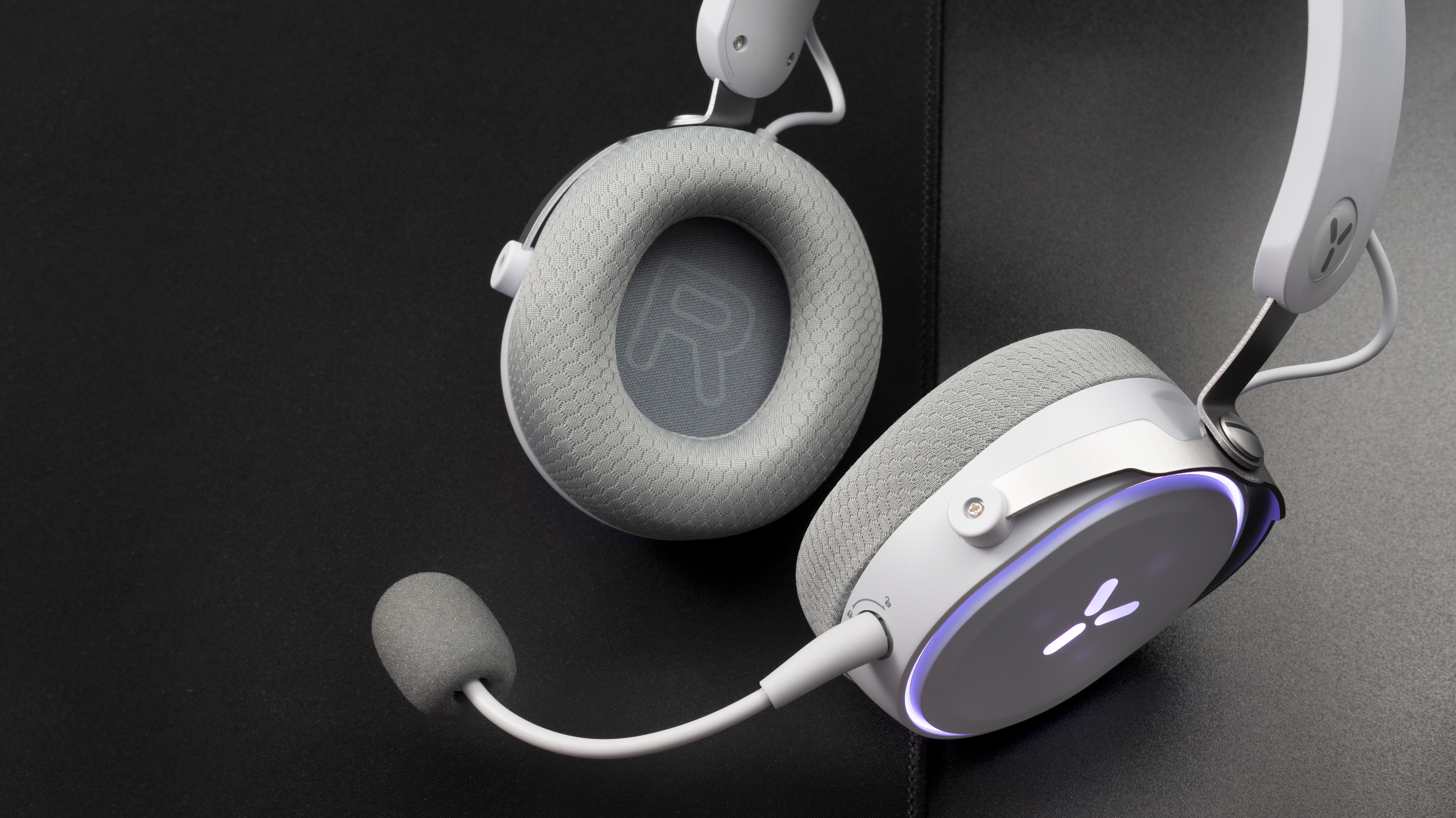 Biało-szare słuchawki dla graczy z mikrofonem na czarnej powierzchni.