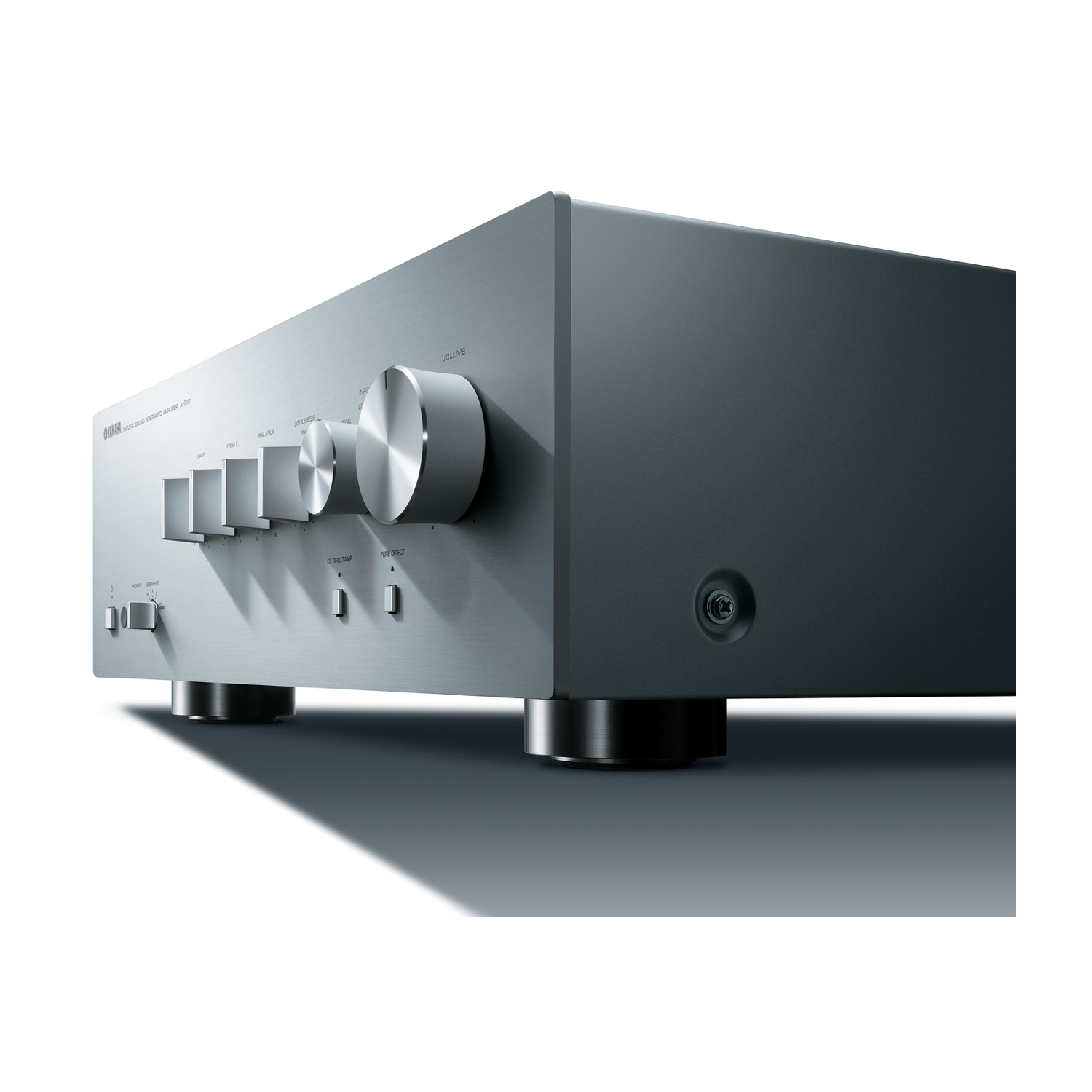 Amplificatore audio argentato con manopole e pulsanti, su superficie bianca, vista angolata.