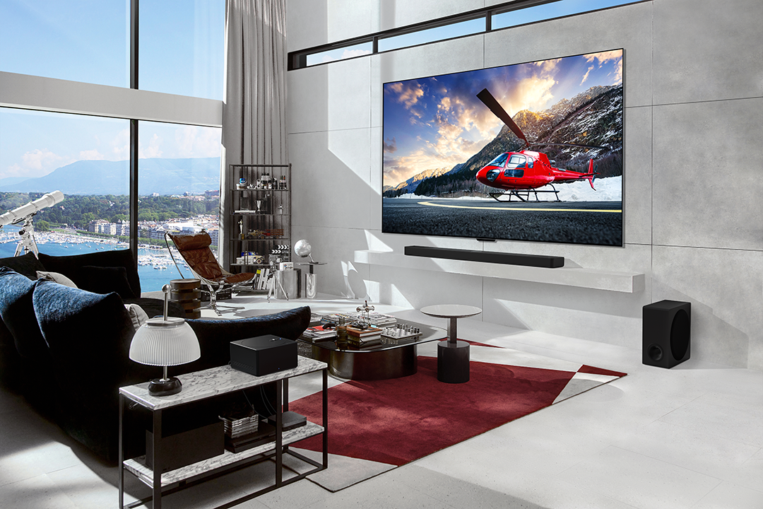 Nappali nagy TV-vel, helikopter jelenettel, modern bútorokkal és dekorációval.