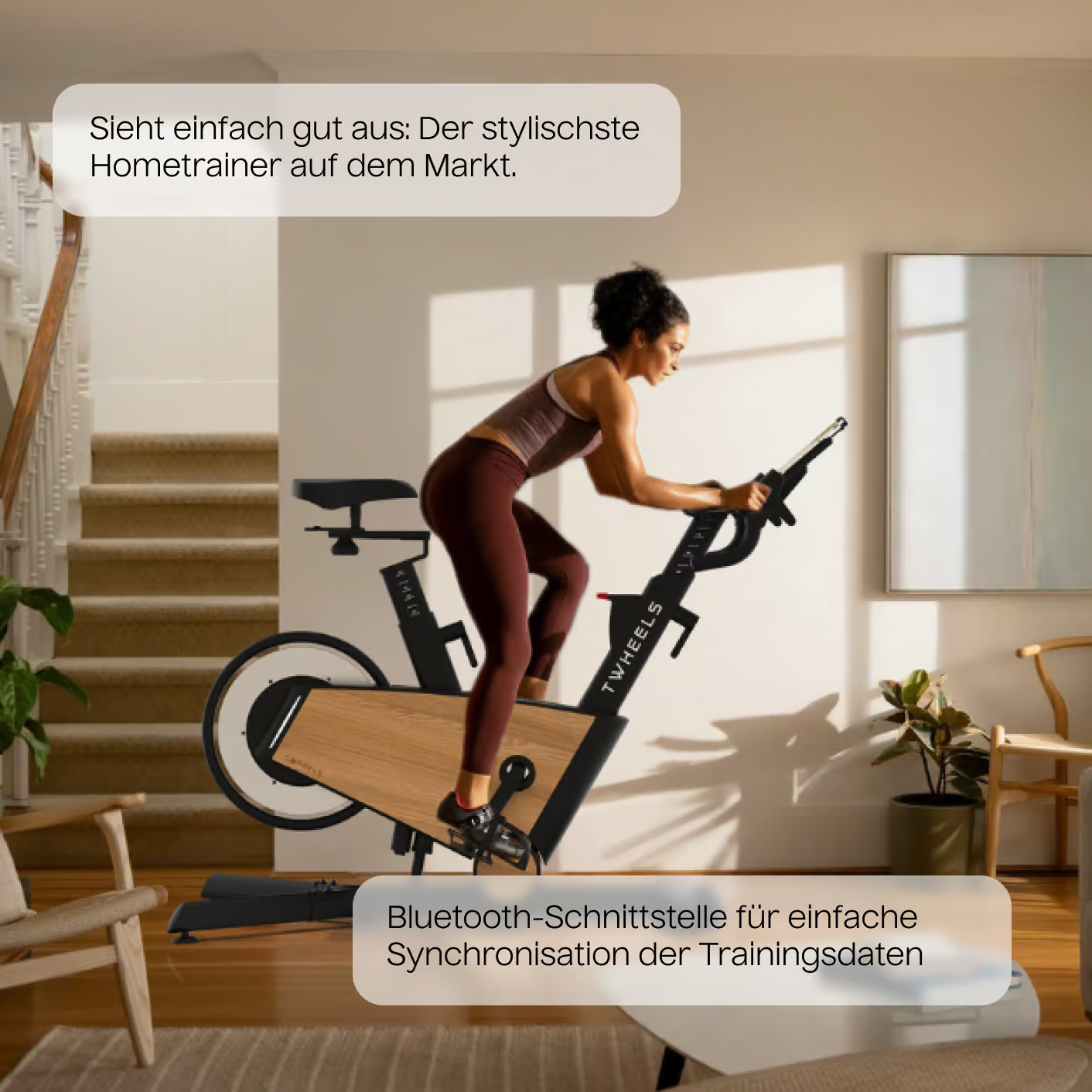 Femme sur un vélo d'exercice noir. Intérieur clair avec escalier et tableau en arrière-plan.