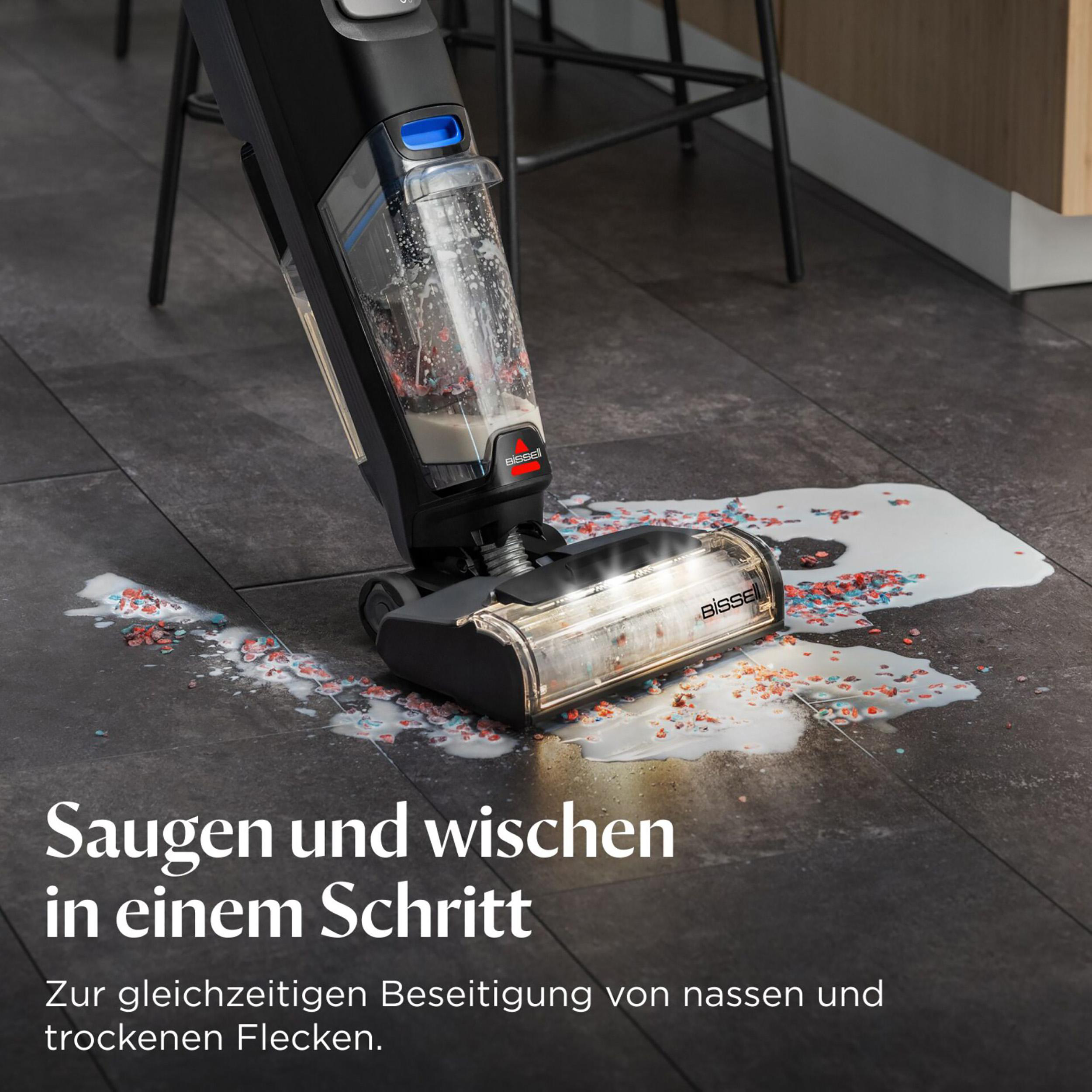 Eine Person reinigt mit einem Bodenreiniger verschüttete bunte Süßigkeiten und Flüssigkeit.