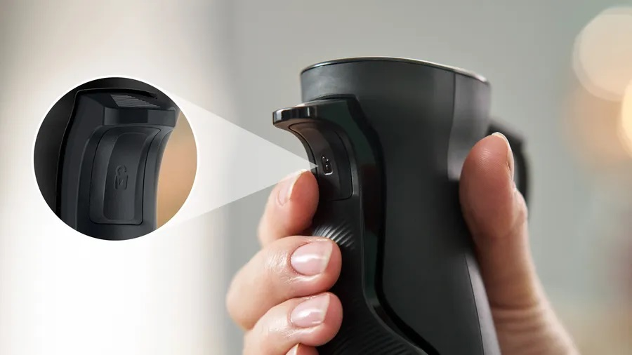 Zbliżenie dłoni trzymającej czarny blender z detalem przycisku.