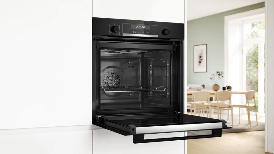 Un forno nero aperto integrato in un mobile bianco.