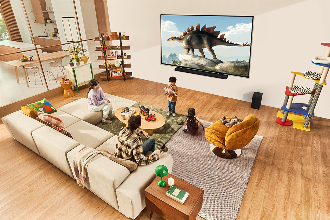 Nappali jelenet családdal, TV dinoszaurusszal, kanapé, szőnyeg és macskatorony.
