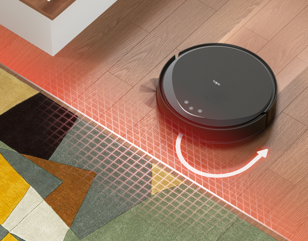 Egy fekete robot porszívó fa padlót tisztít.