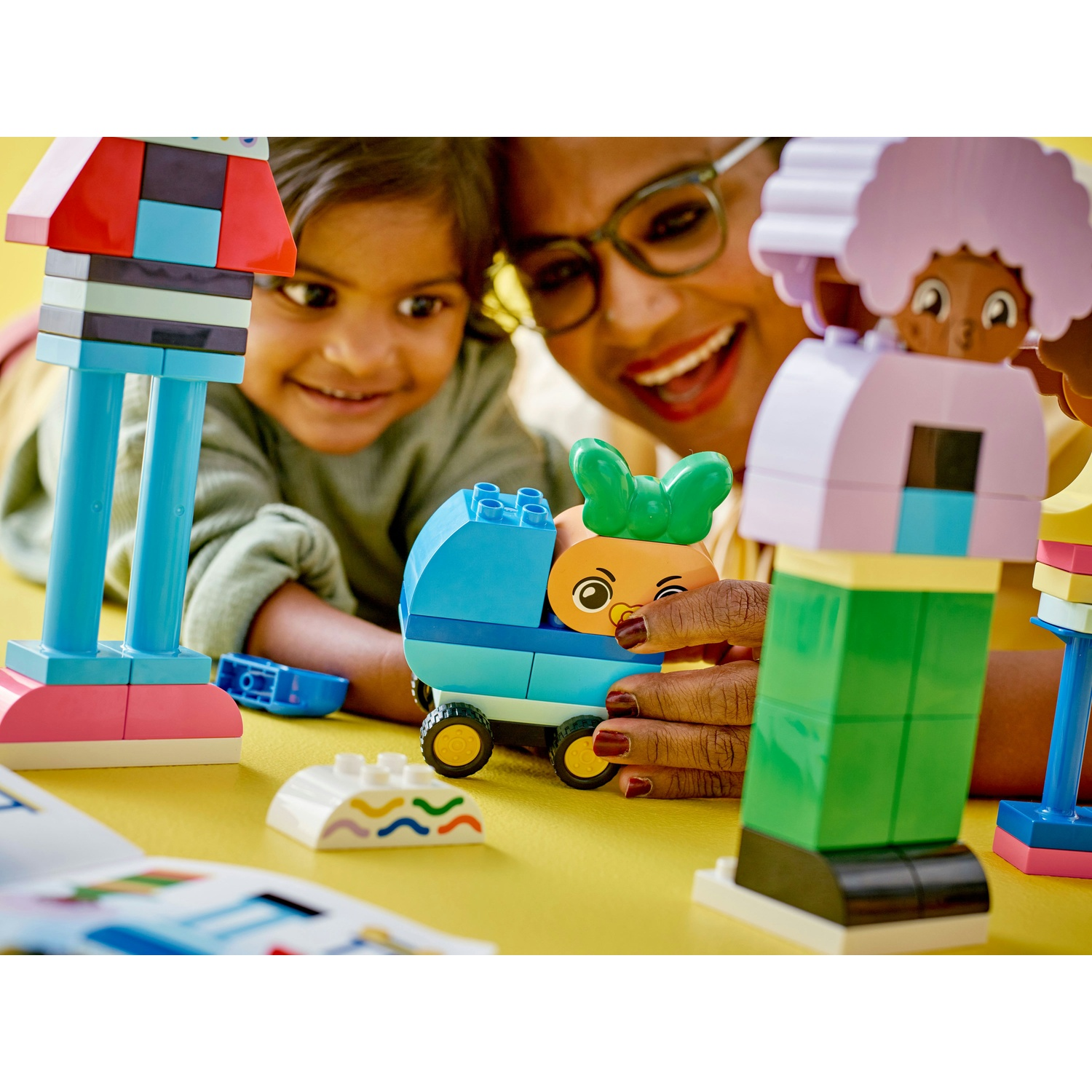 Una donna e una bambina giocano con i mattoncini Lego Duplo. Stanno sorridendo.