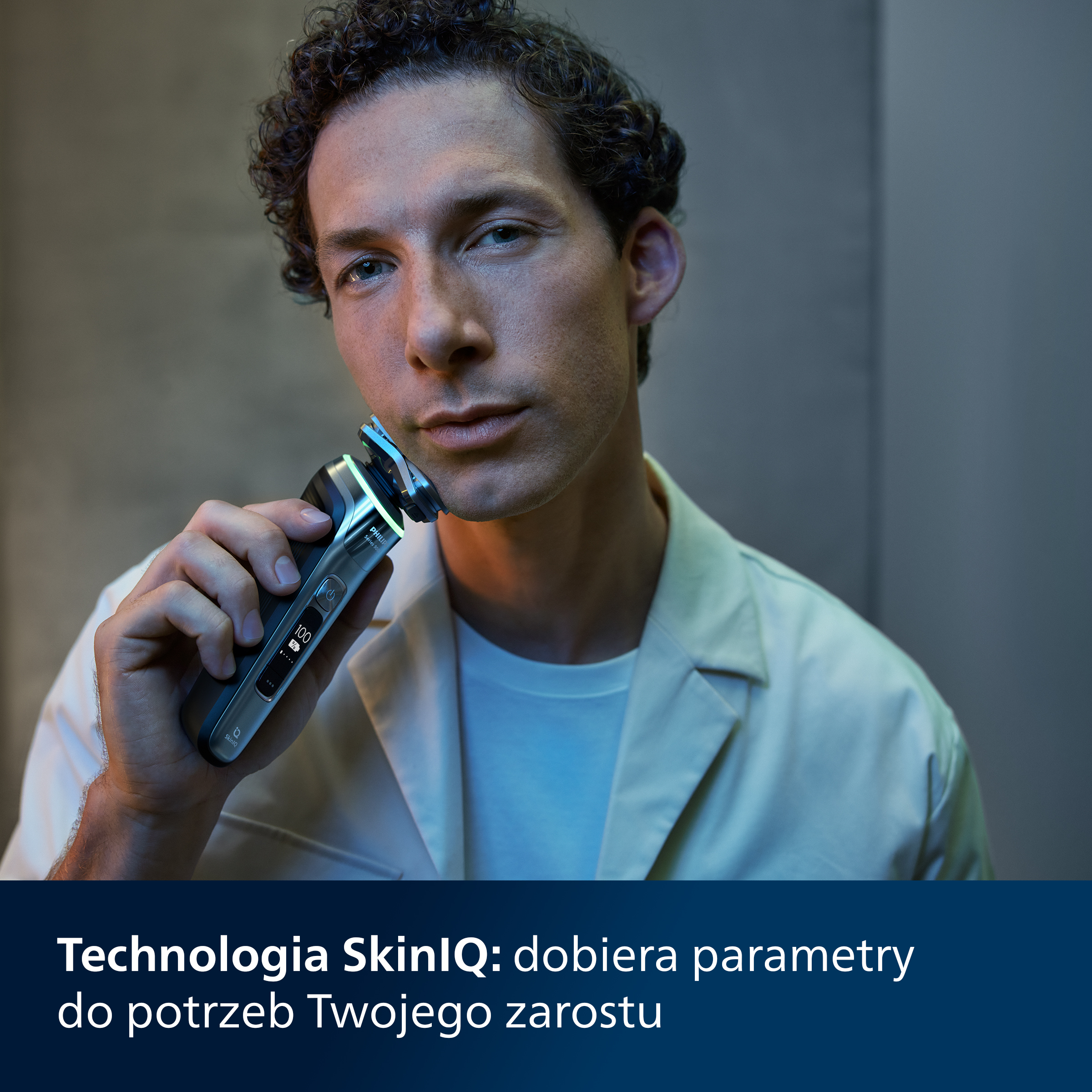 Mężczyzna goli się srebrno-czarną golarką elektryczną.