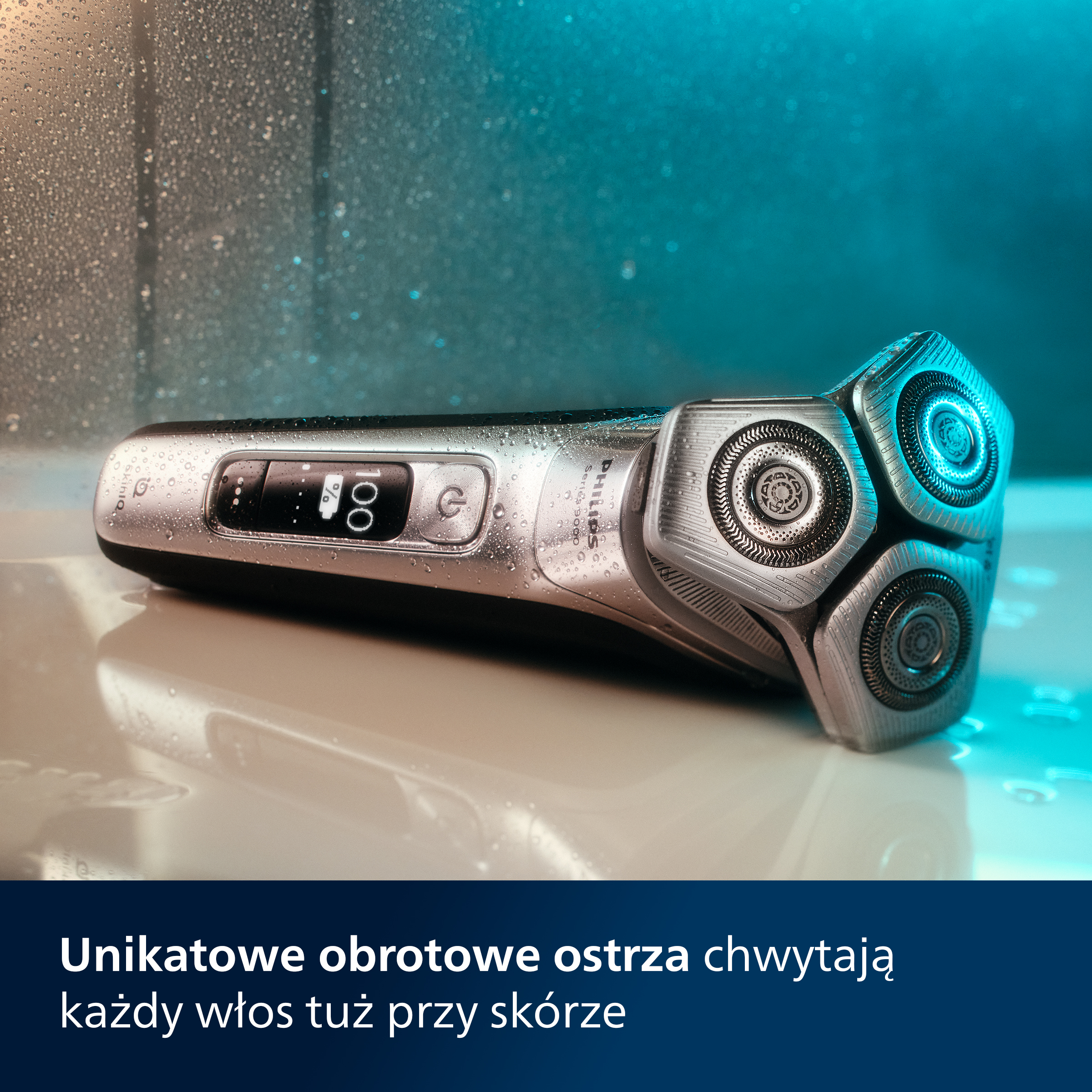 Srebrna golarka elektryczna z trzema głowicami obrotowymi, na mokrej powierzchni.