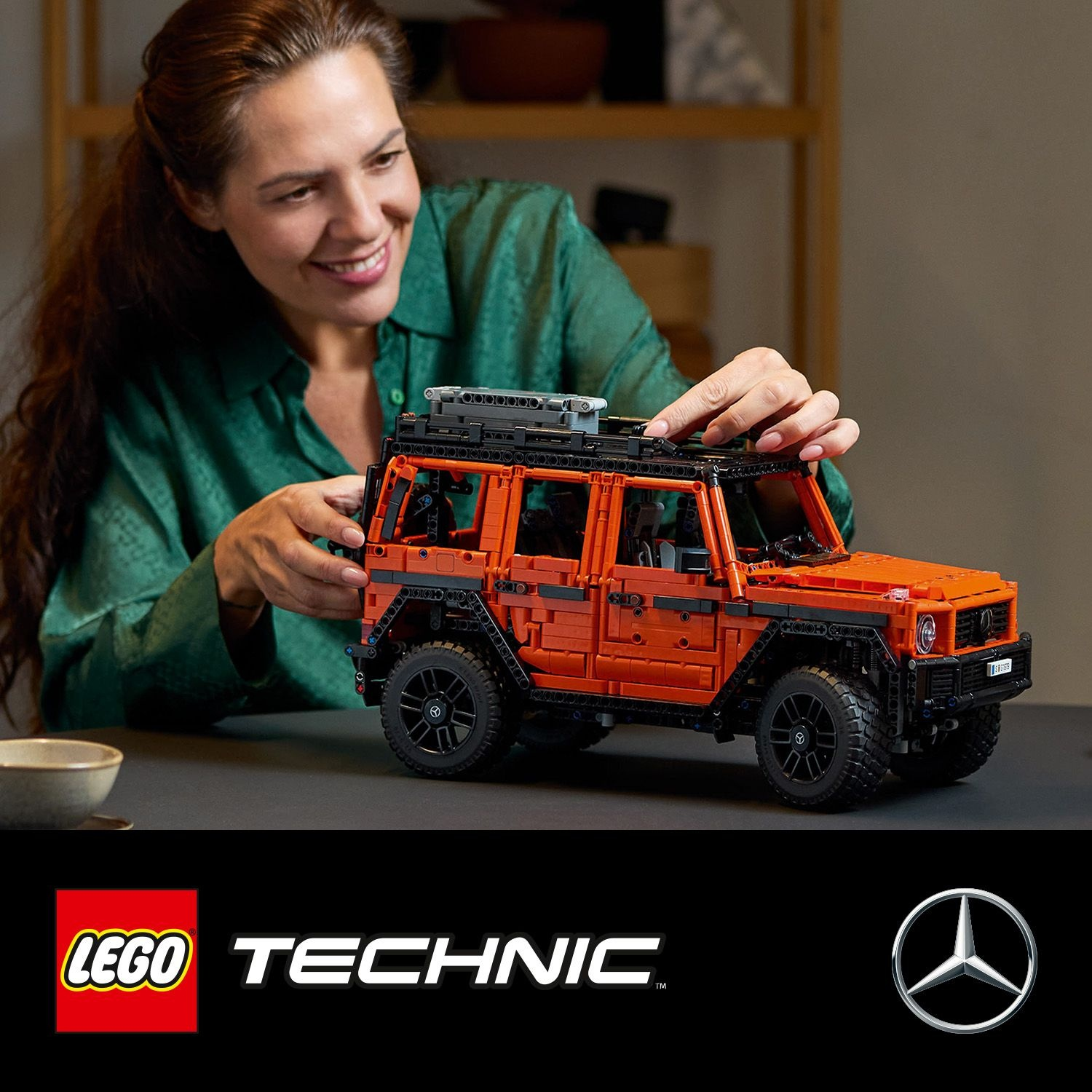 Una donna che costruisce una Mercedes arancione Lego Technic.