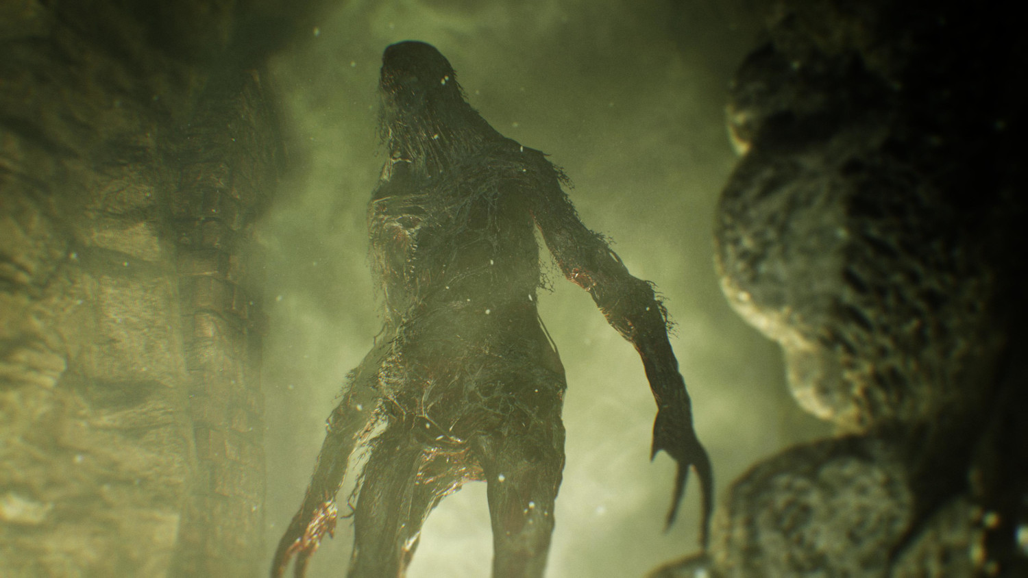 Un monstre dans une grotte. Il est grand et a de longs bras. La grotte est sombre et verte.