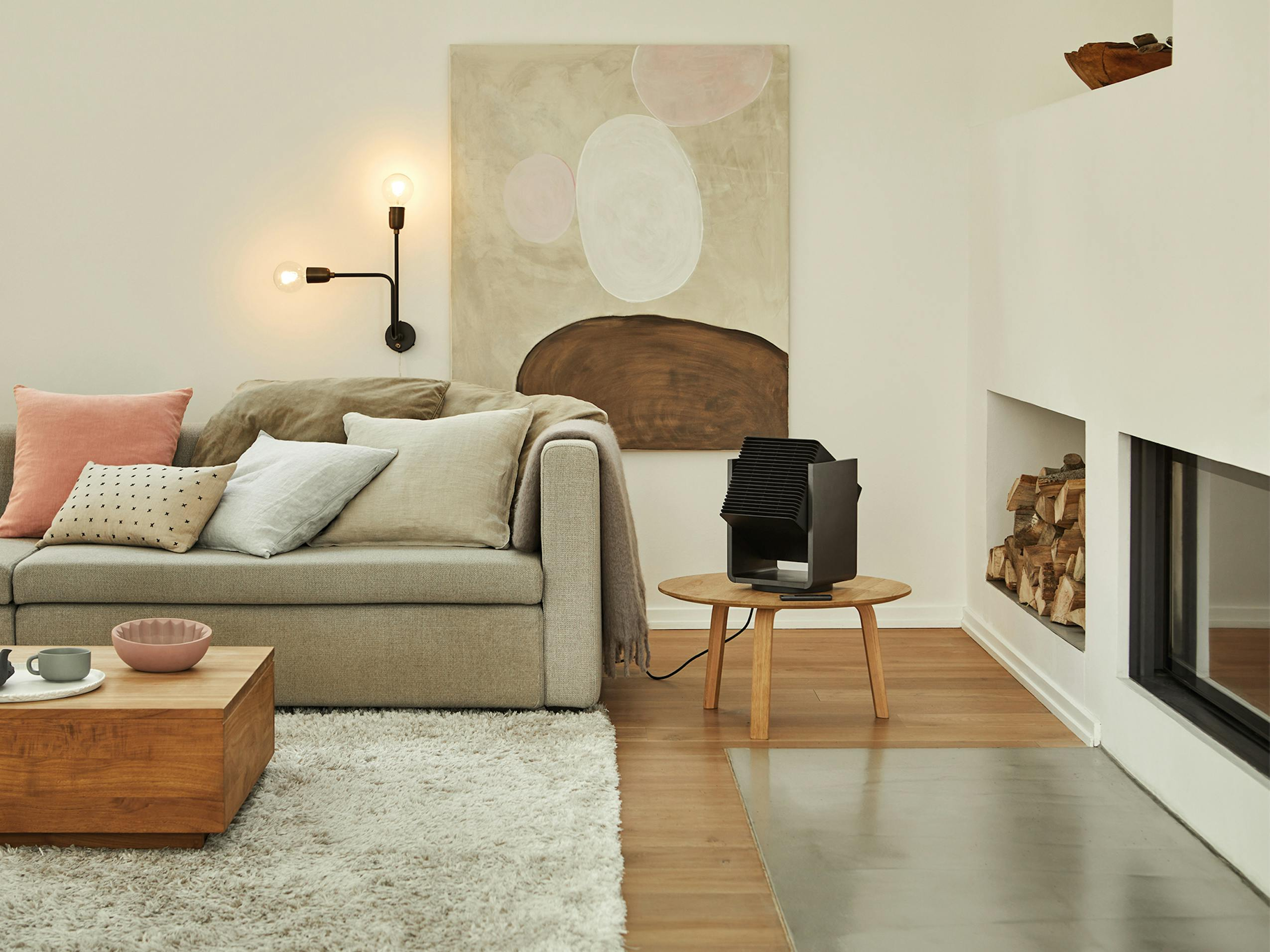Wohnzimmer mit Sofa, Kunst, Lampe, Teppich, Tisch und einem schwarzen Luftreiniger.