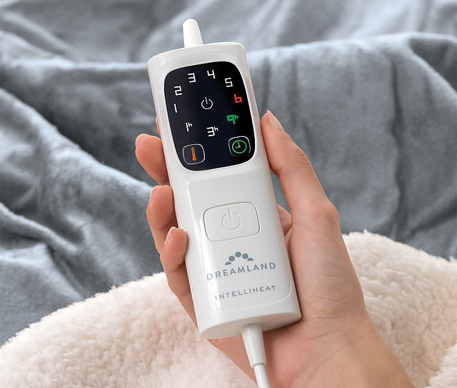 Mano che tiene un telecomando bianco per coperta termica con impostazioni numerate e pulsante di accensione.