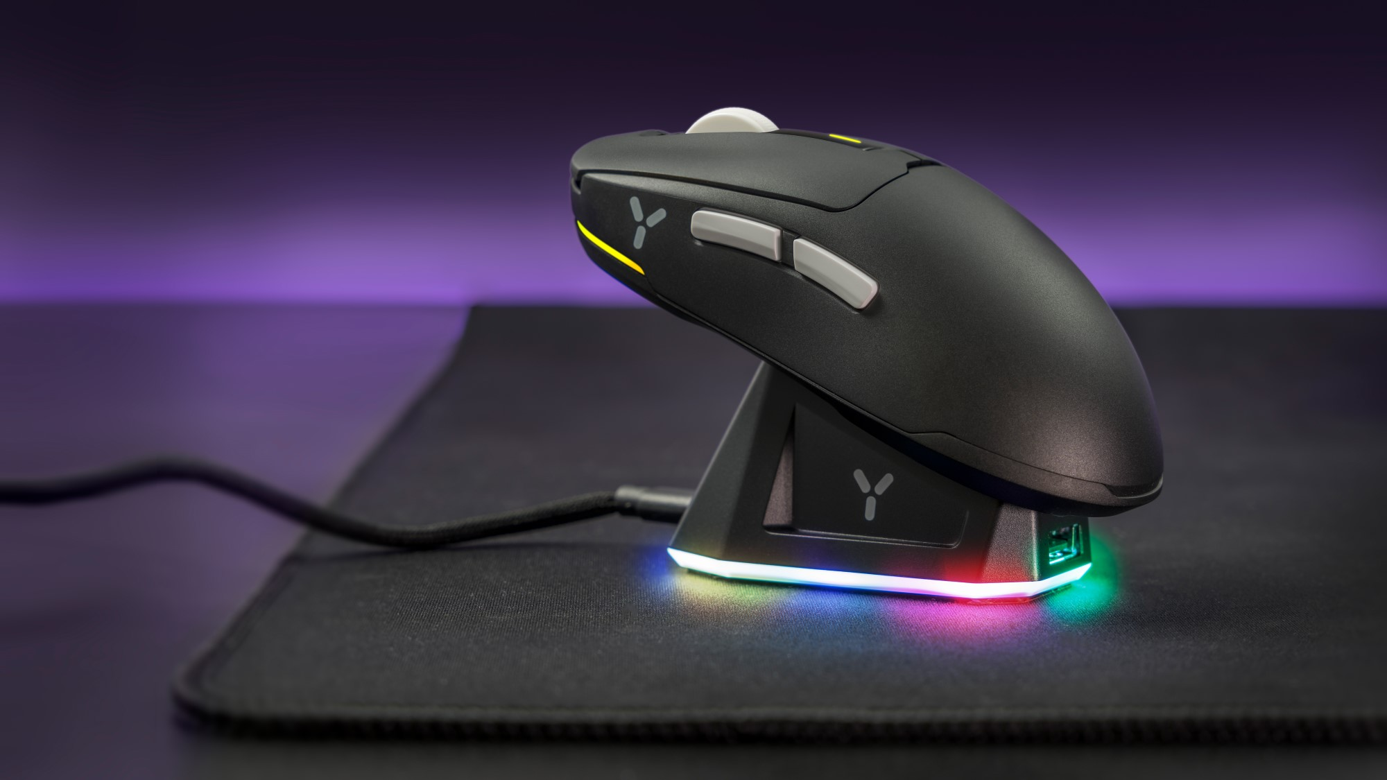 Czarna mysz gamingowa na stacji ładującej, z podświetleniem RGB. Fioletowe tło i czarna podkładka.