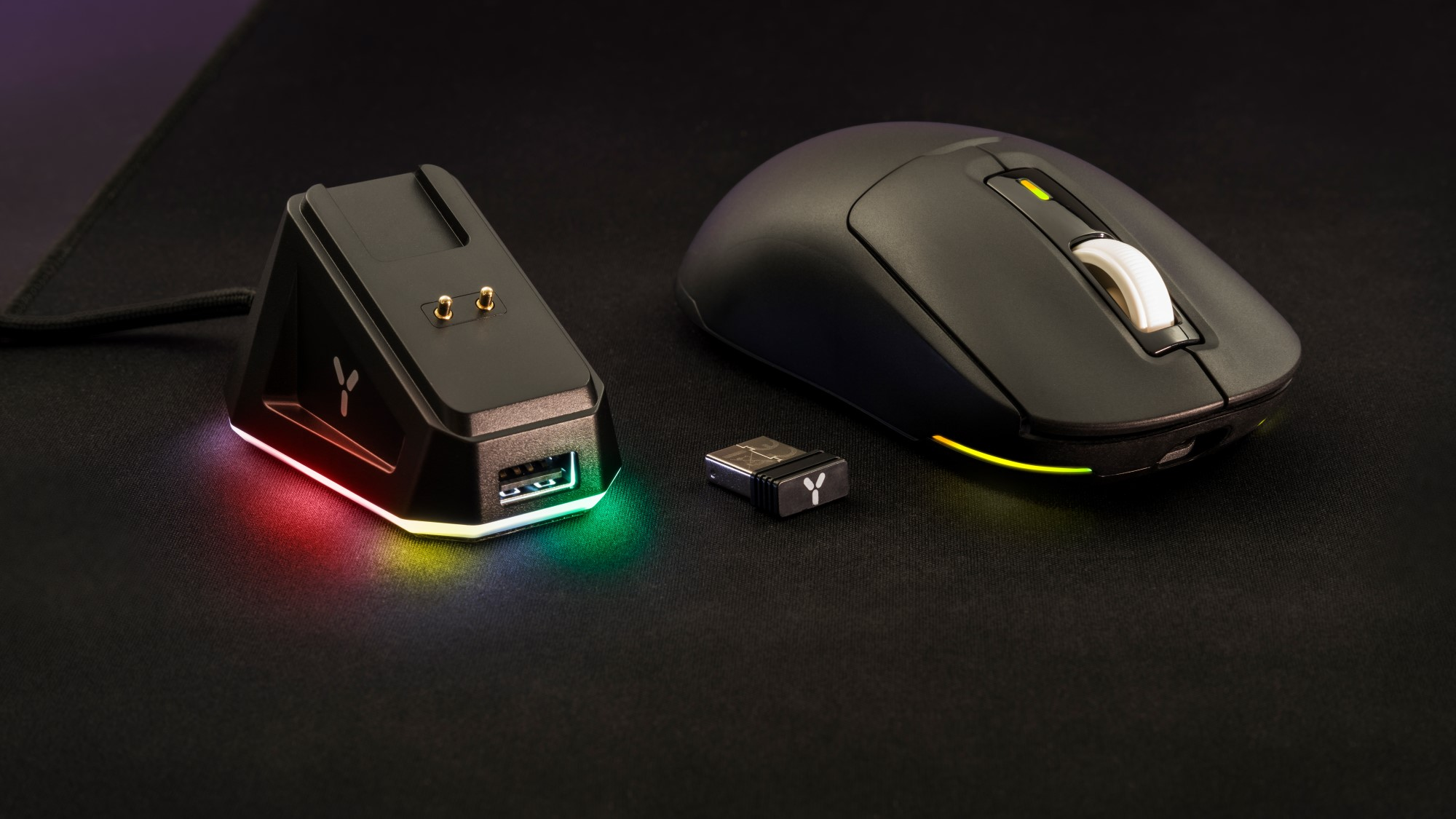 Czarna mysz, stacja ładująca i klucz USB na czarnej powierzchni.