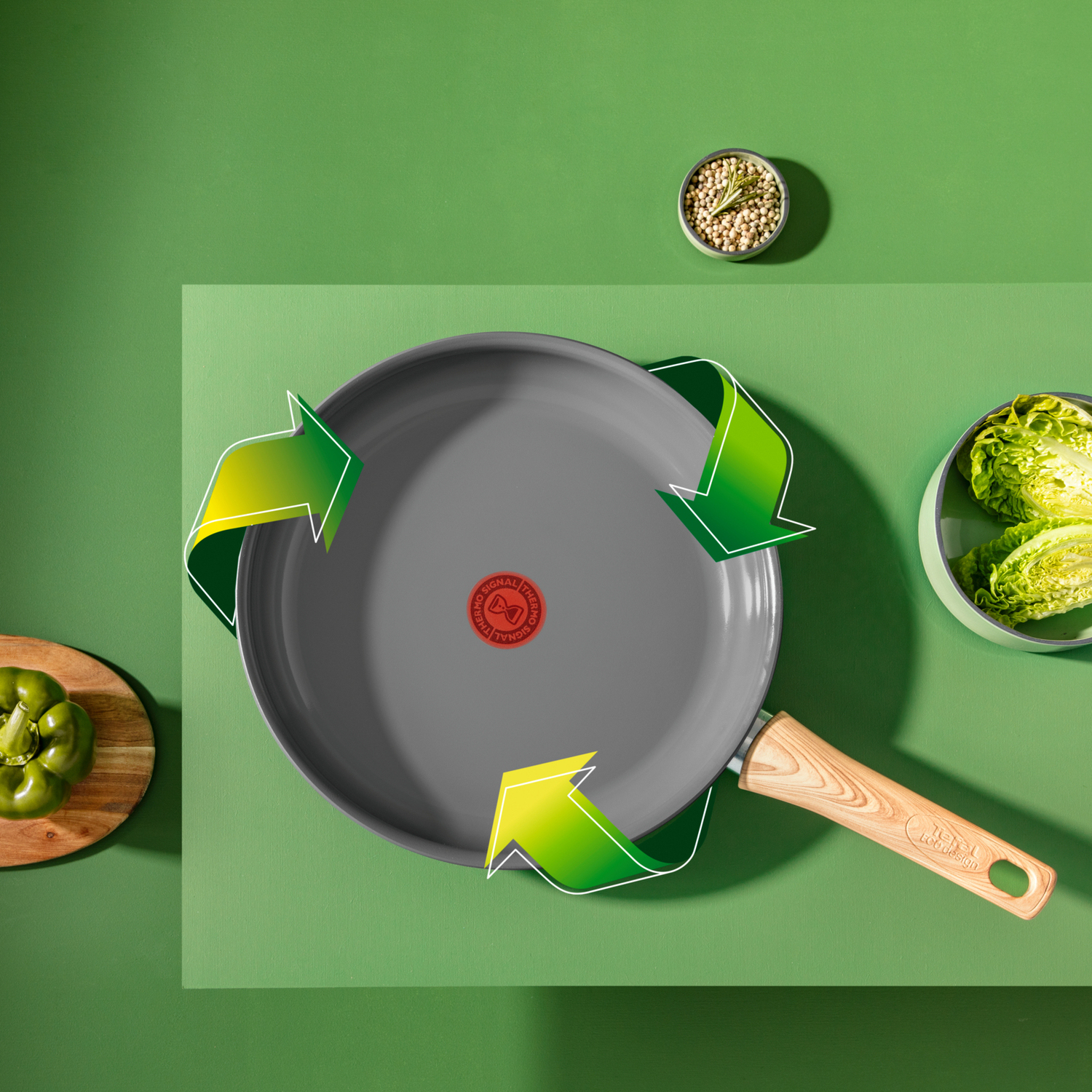 Een grijze pan met groene pijlen, groene achtergrond en groenten.