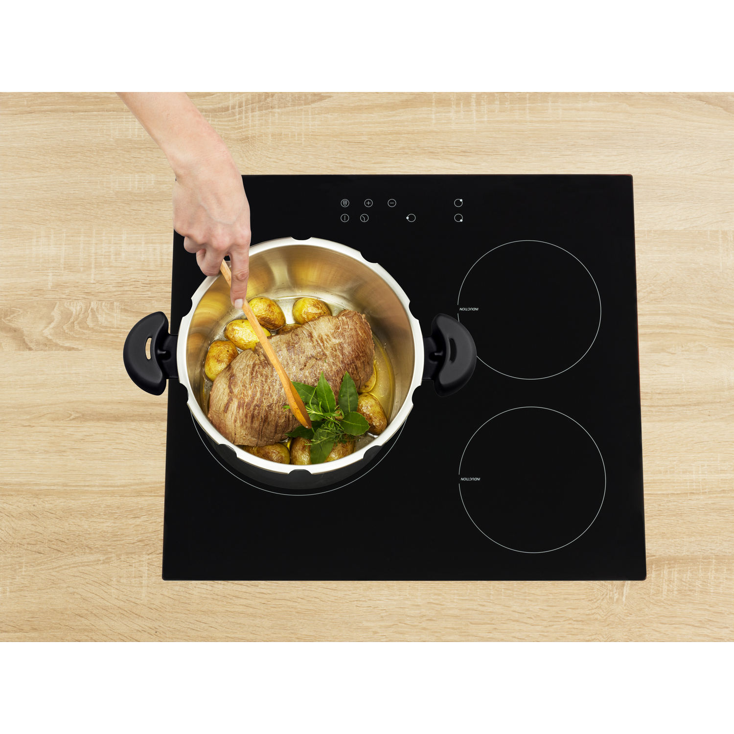 A hand stirring food in a pot on a black stovetop with two burners.