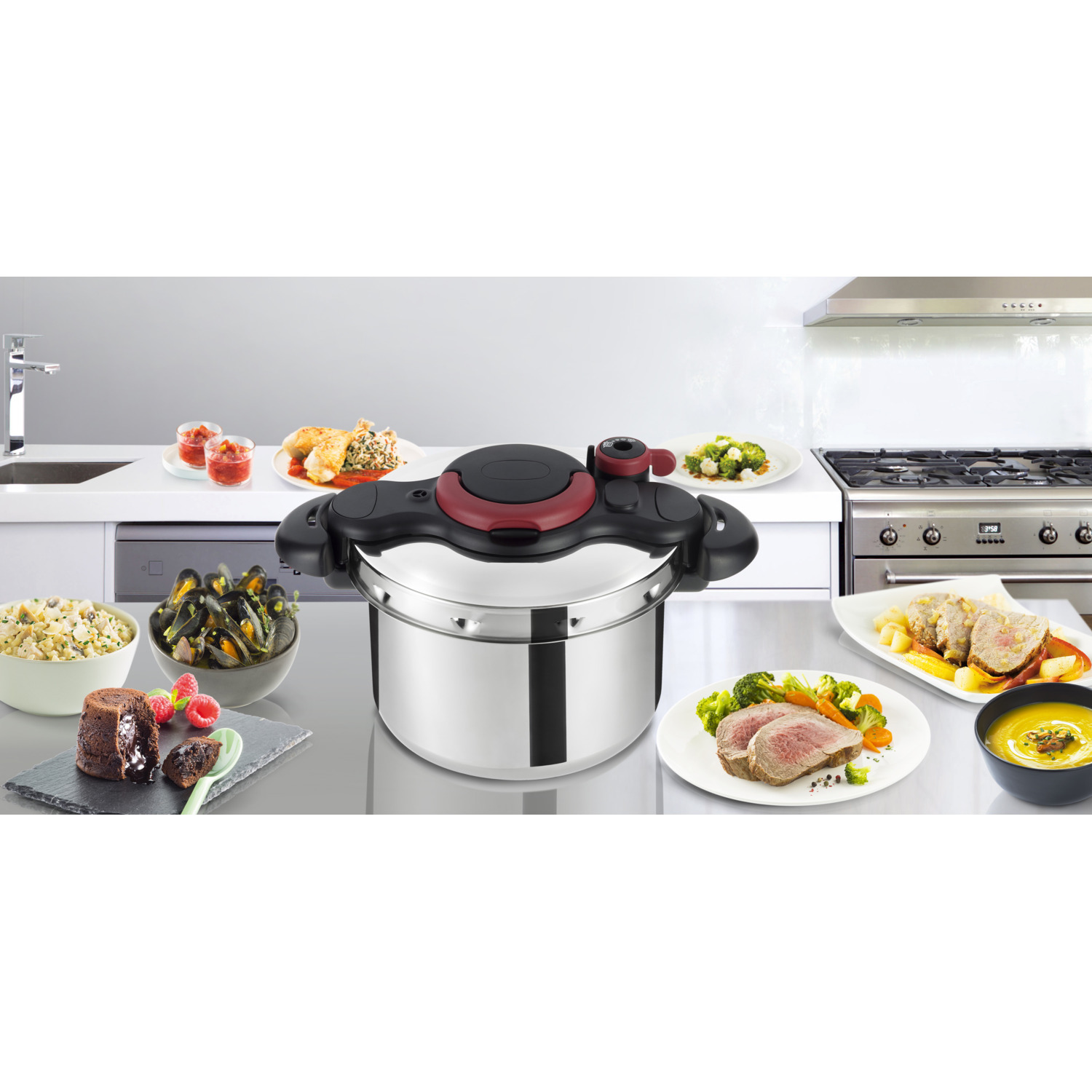 A stainless steel pressure cooker with food arranged around it, on a reflective surface, in a kitchen.