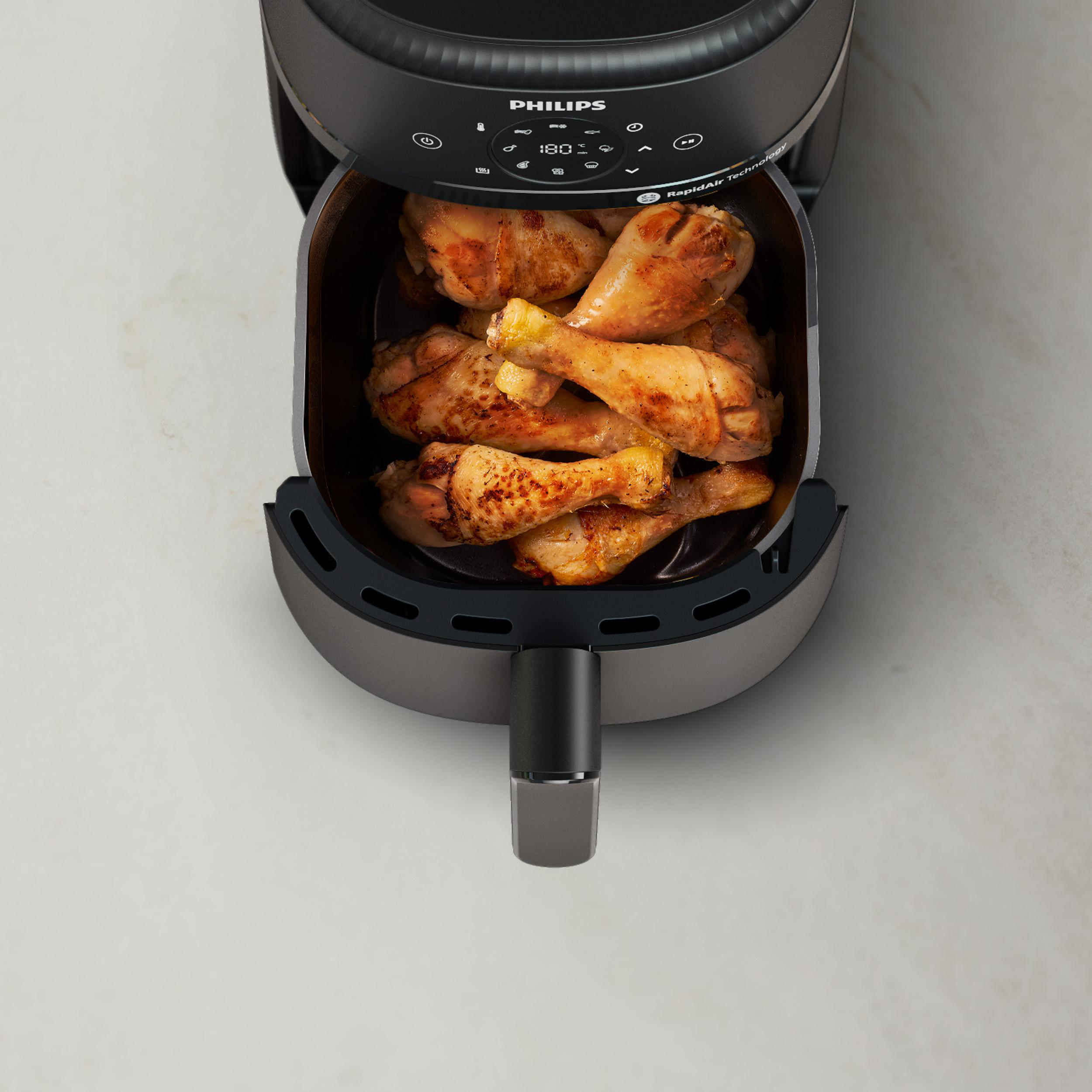 Ein Philips Heißluftfritteusenkorb mit gebratenen Hähnchenschenkeln.