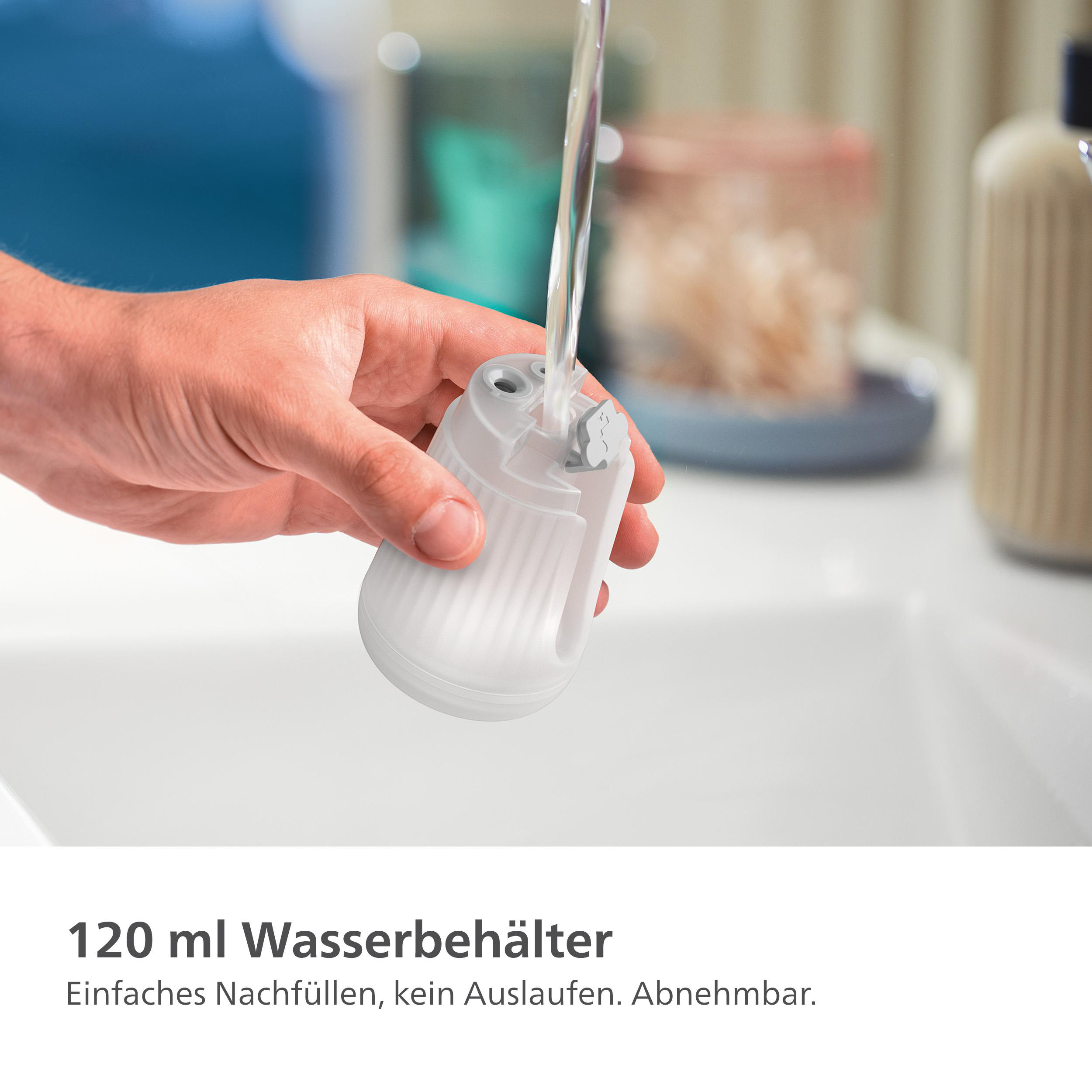 Eine Hand hält einen weißen Behälter mit Wasser und Filter über einem Waschbecken.