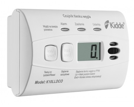 Biały czujnik tlenku węgla Kidde z cyfrowym wyświetlaczem, pokazujący odczyt 0,0 i kilka kontrolek.