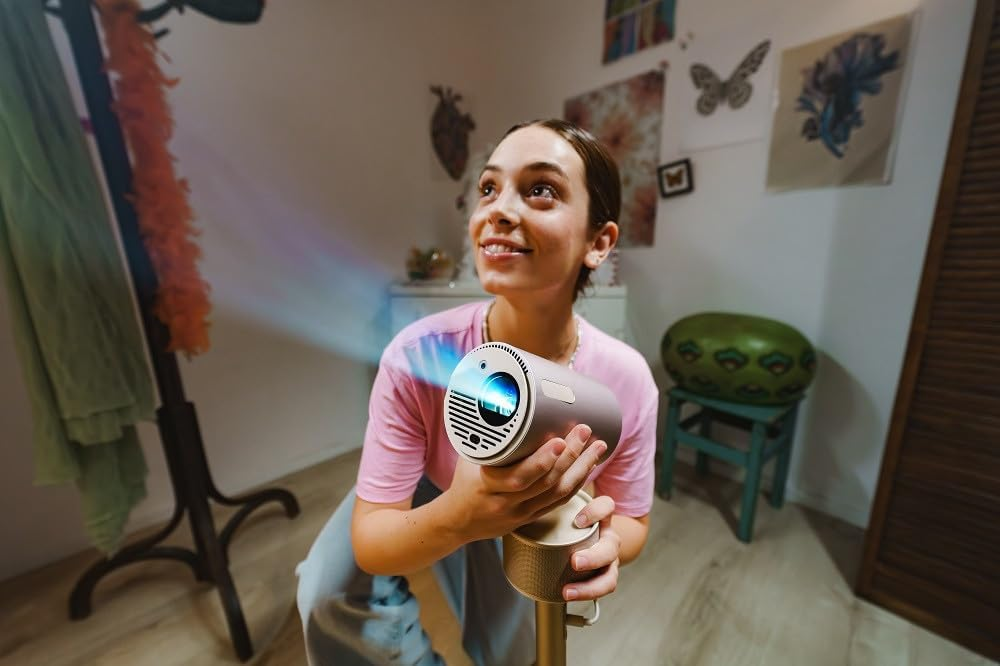 Una mujer sostiene un proyector pequeño, sonriendo hacia arriba, con un fondo moderno y colorido.