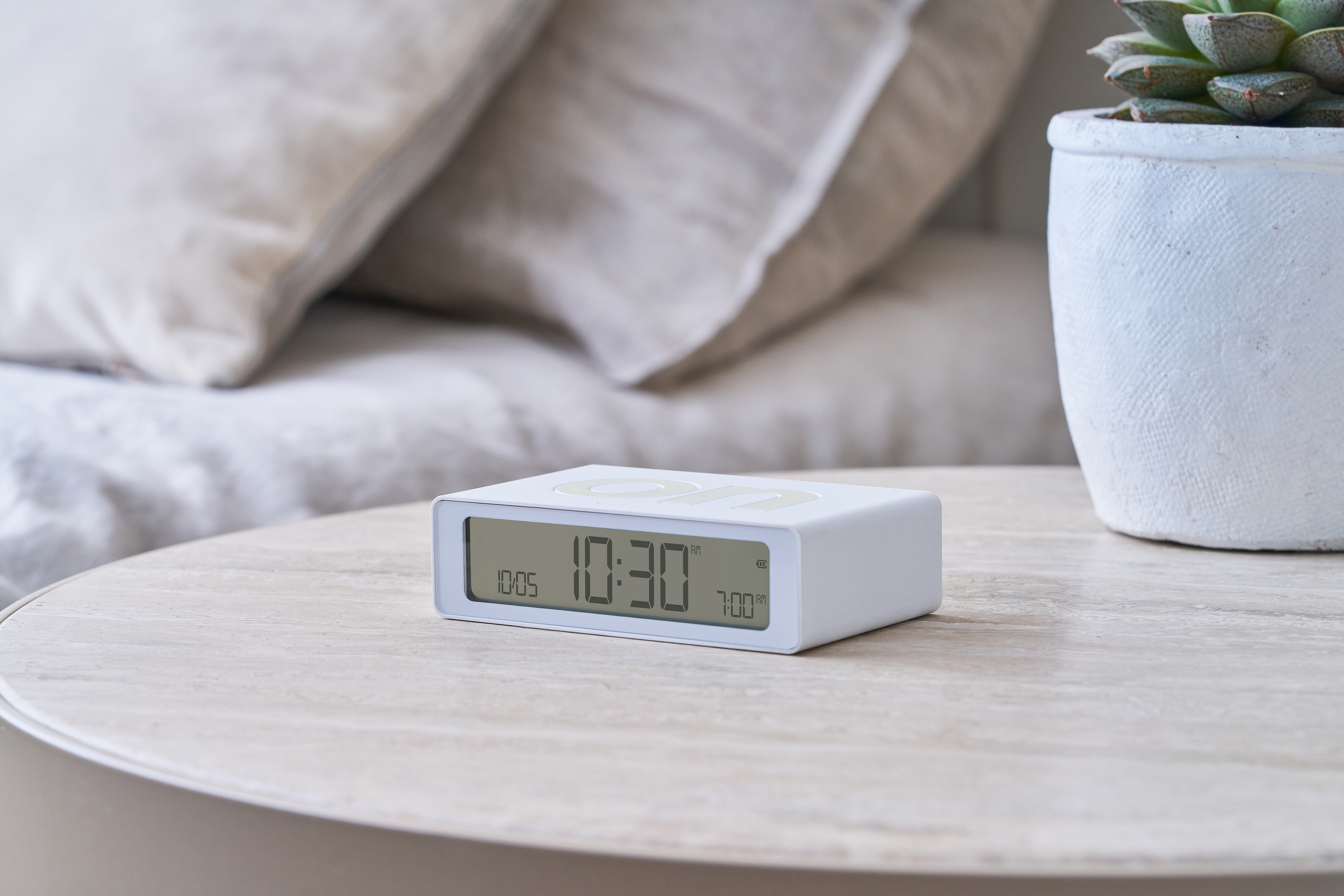 Orologio rettangolare bianco su un tavolo, che mostra le 10:30 e altri orari.