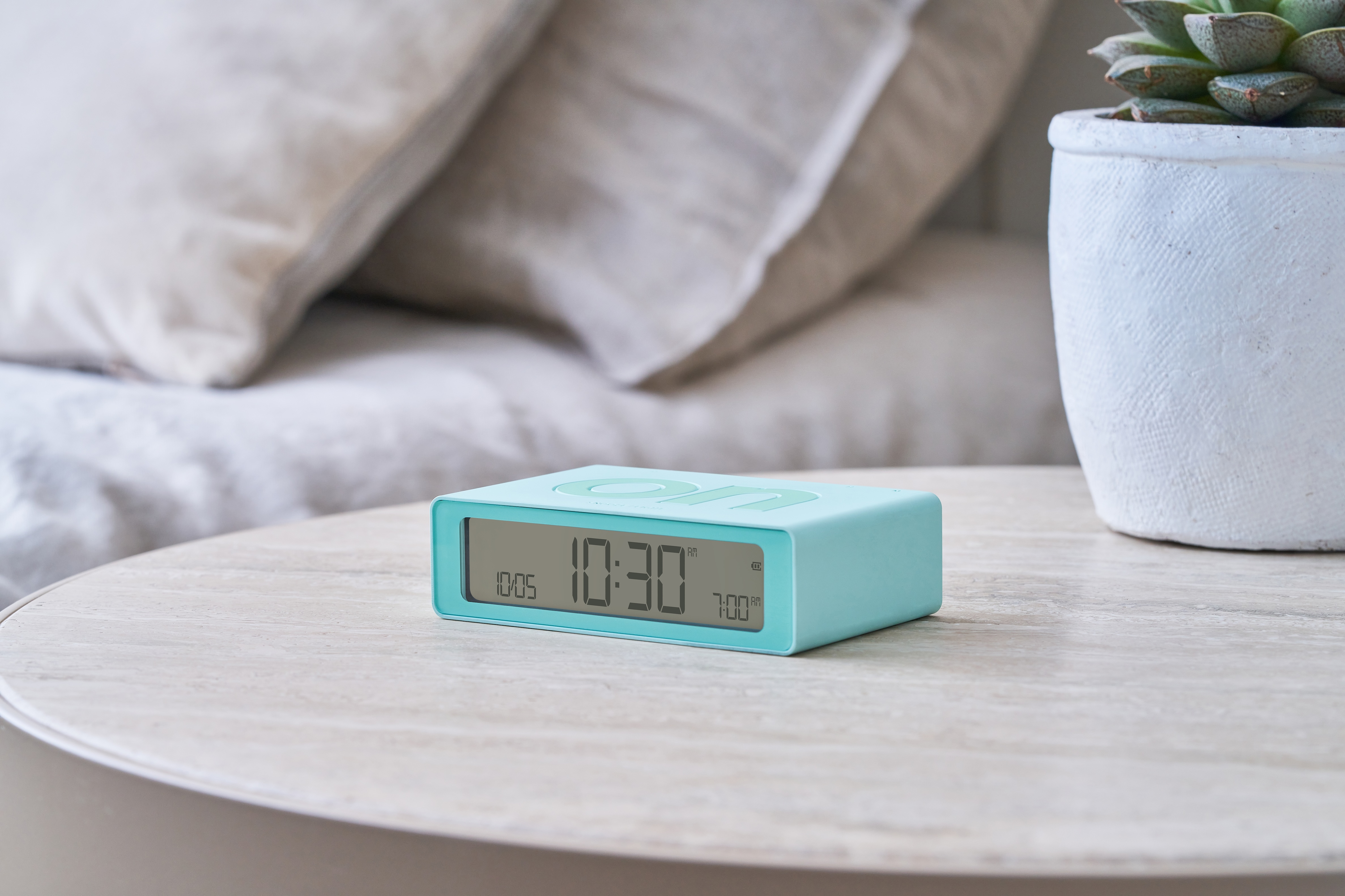 Sveglia blu su un tavolo di legno, che mostra le 10:30 e la data 10/05. La parola 'on' è visibile.