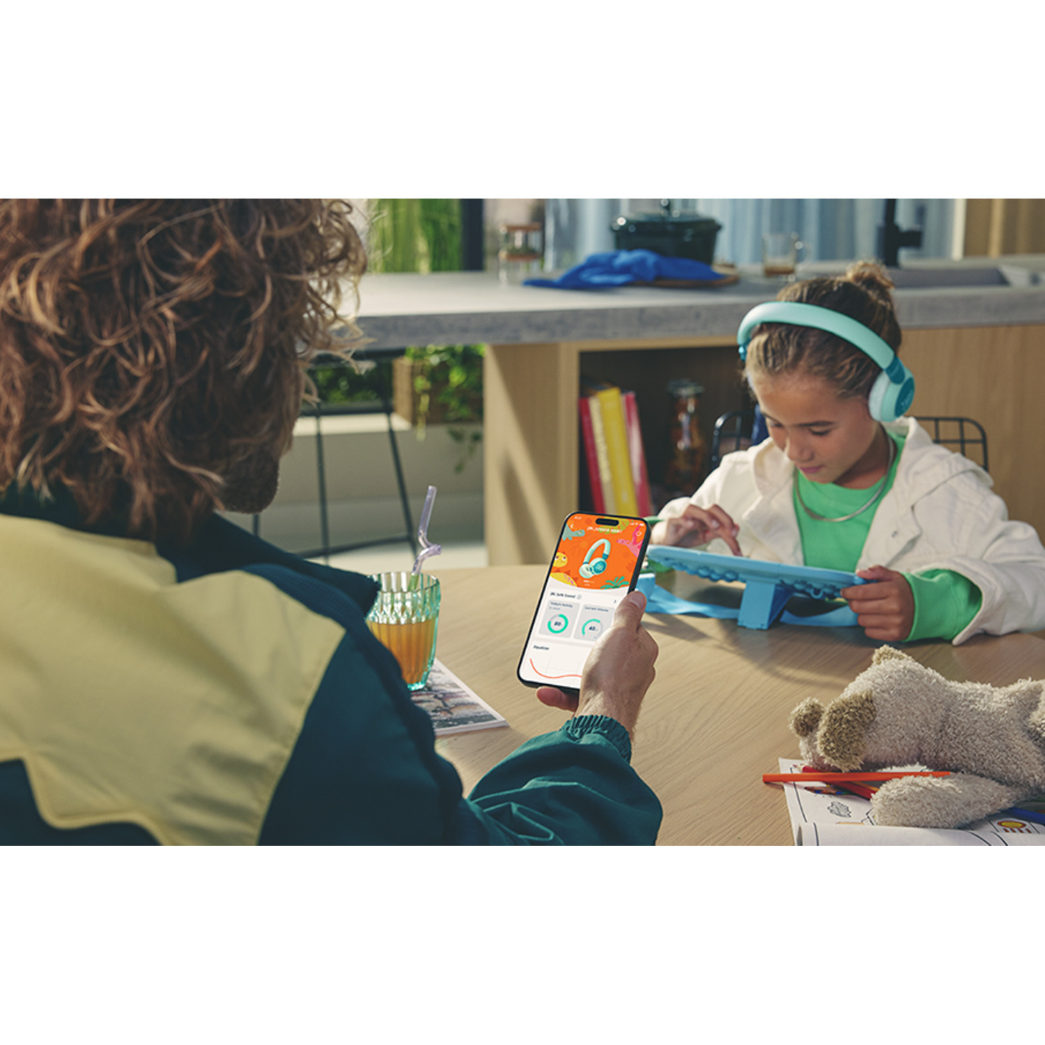 Un enfant portant un casque regarde un téléphone avec un adulte.