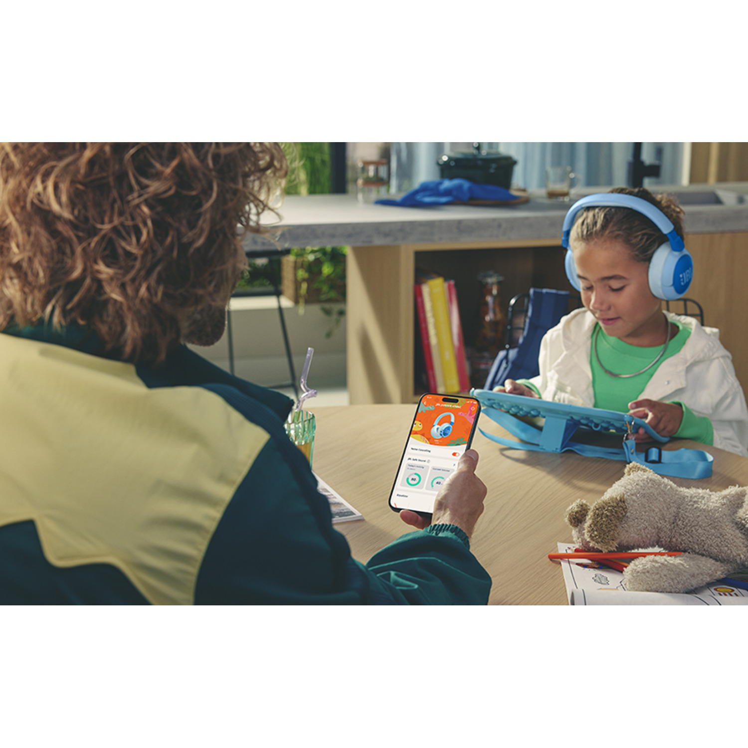 Une personne utilisant un téléphone montrant des écouteurs, avec une fille portant des écouteurs bleus.