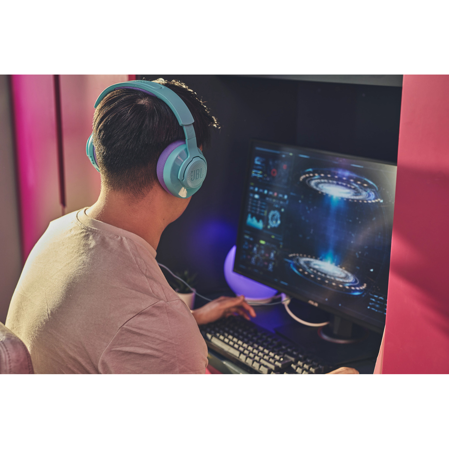 Man met blauwe gaming-koptelefoon, aan het gamen op een computer. Hij is gefocust op het scherm.
