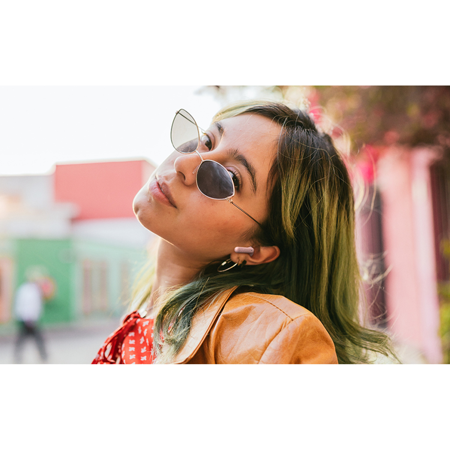 Woman wearing sunglasses and earbuds, head tilted back.