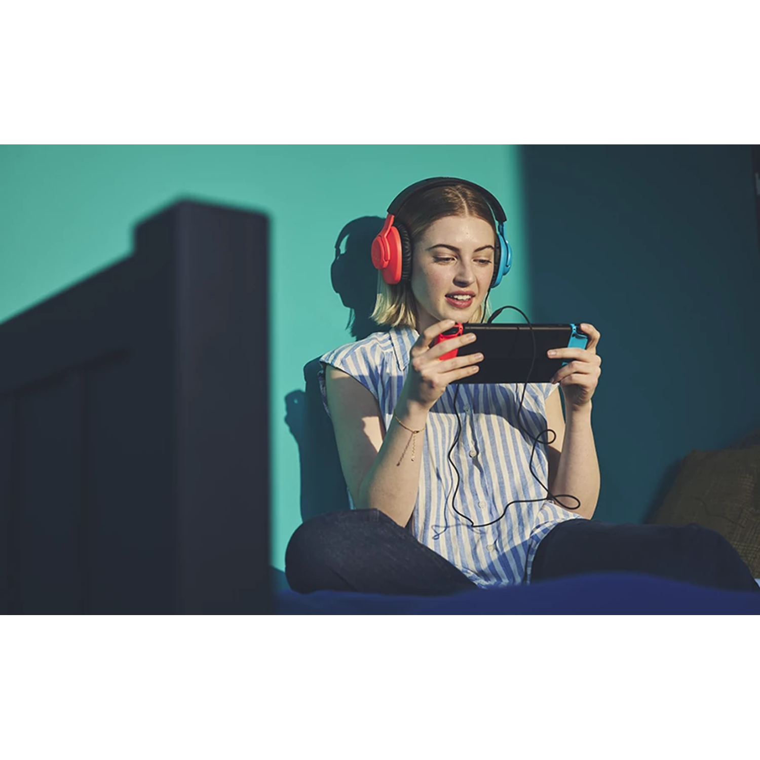 Blonde woman playing a handheld game with headphones.