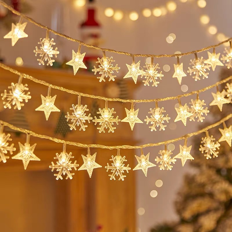 Światełka bożonarodzeniowe w kształcie gwiazd i płatków śniegu wiszące w pokoju.