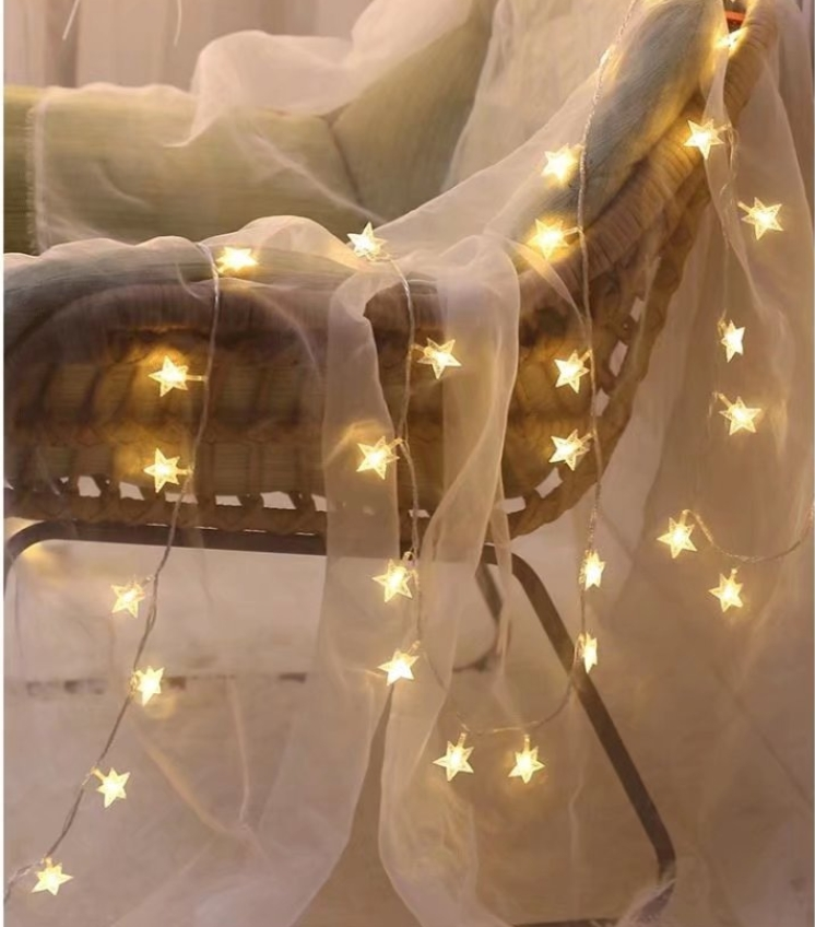 Szereg świateł w kształcie gwiazd, przerzuconych przez krzesło z przezroczystą tkaniną.