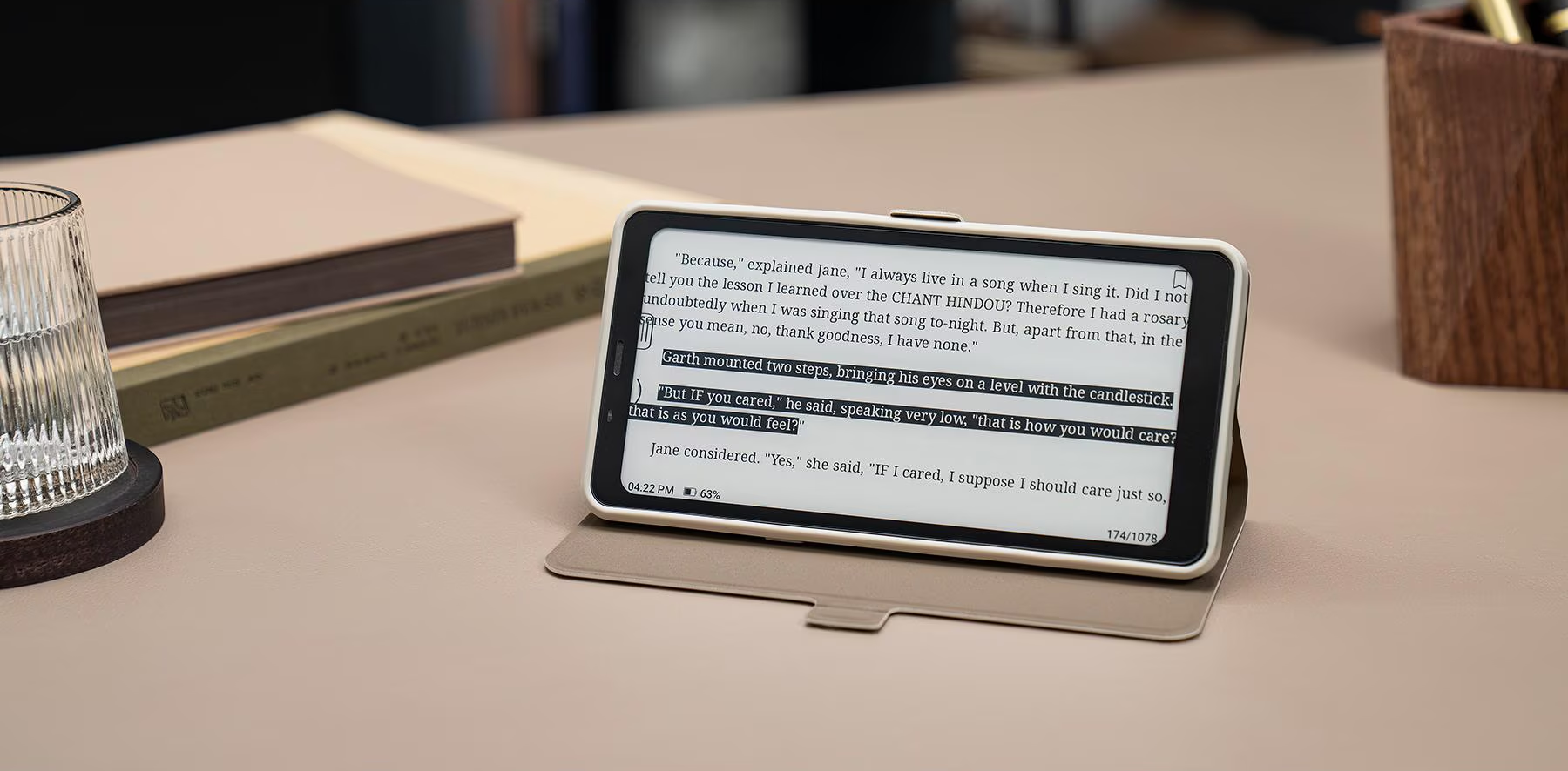 Ein Tablet mit einem offenen Buch darauf. Das Tablet befindet sich in einer Hülle. Daneben Bücher und ein Untersetzer.