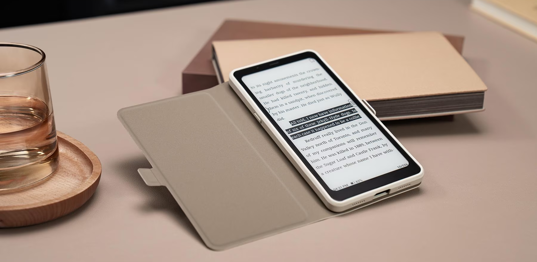 Ein offenes Buch liegt auf einem Tisch neben einem Smartphone, das Text anzeigt. Ein Glas Wasser ist vorhanden.