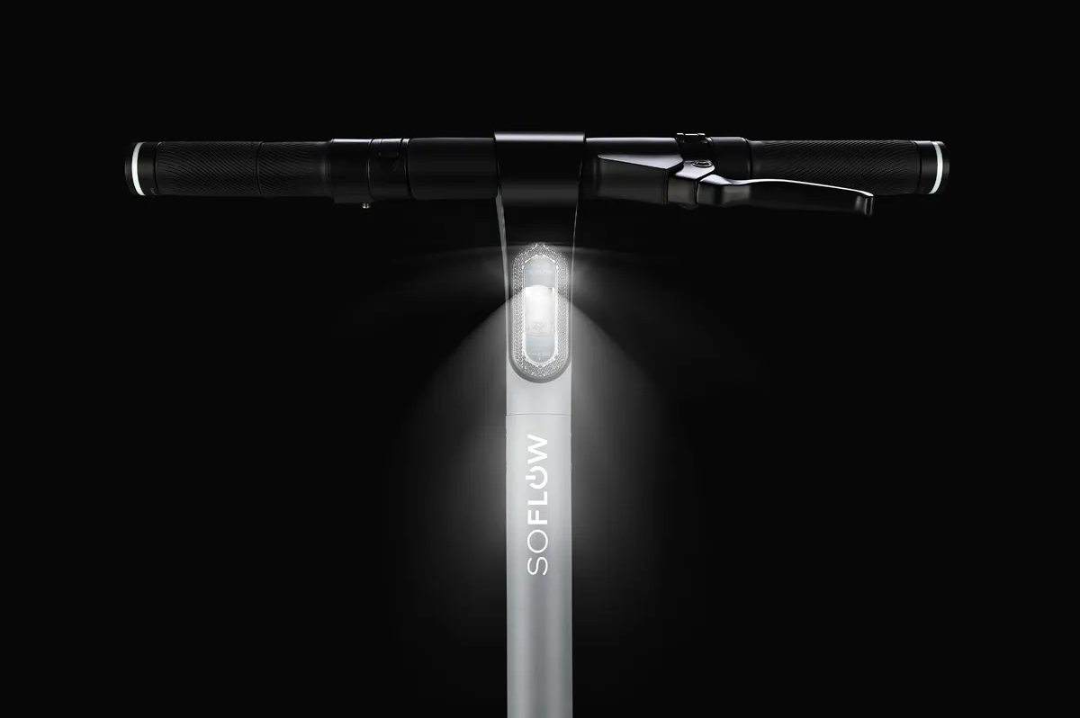 Gros plan sur le guidon gris d'une trottinette électrique SOFLOW, éclairé sur fond noir.
