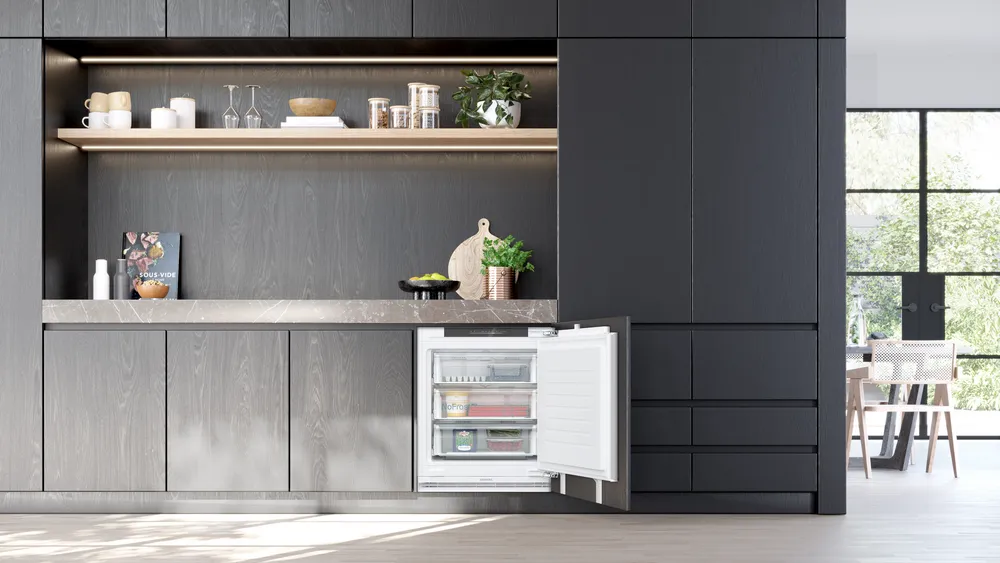 Cucina moderna con mobili e frigorifero. Porta frigo aperta rivela alimenti. Legno scuro.
