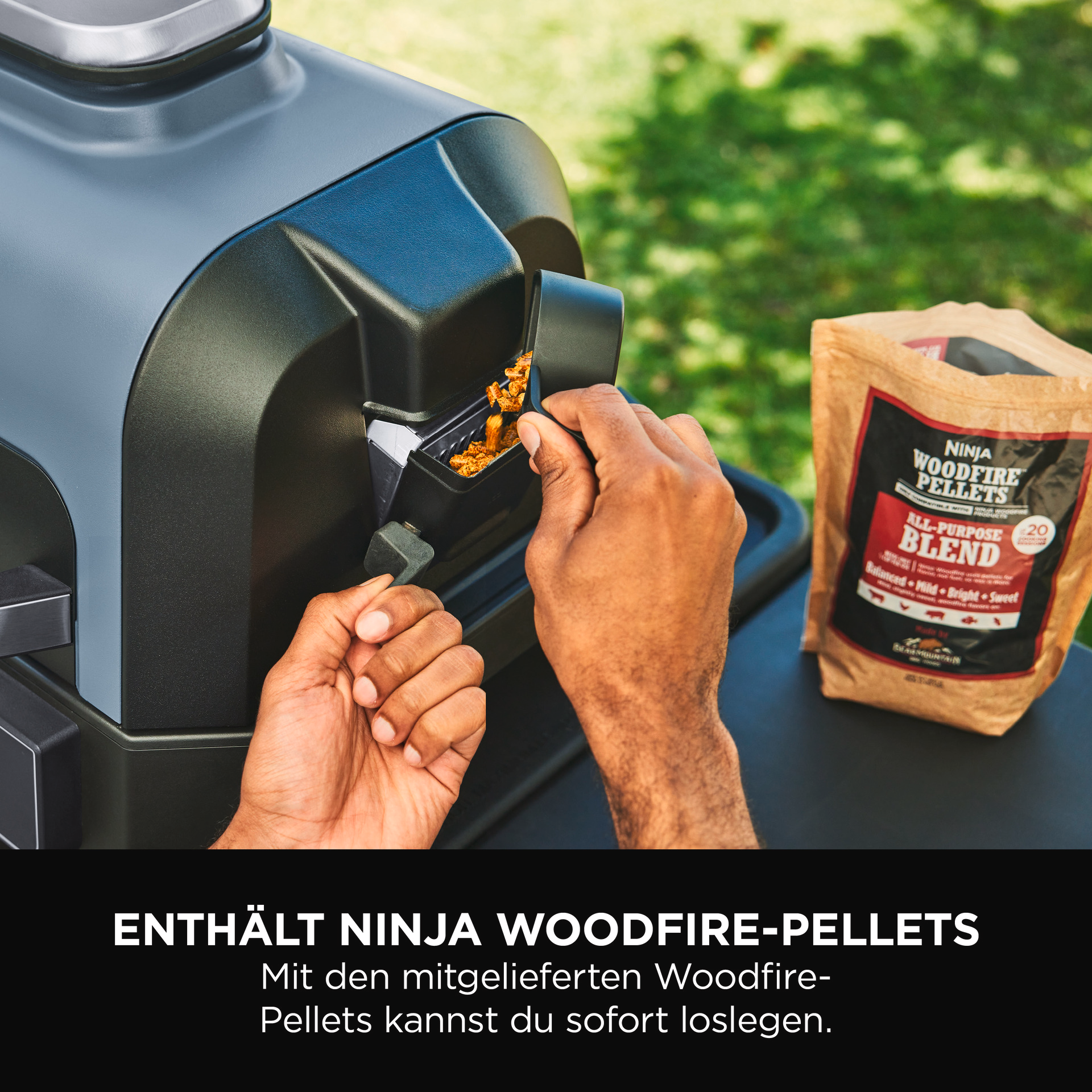 Person fügt Holzpellets in einen Grill. Rechts ist eine Tüte Pellets.