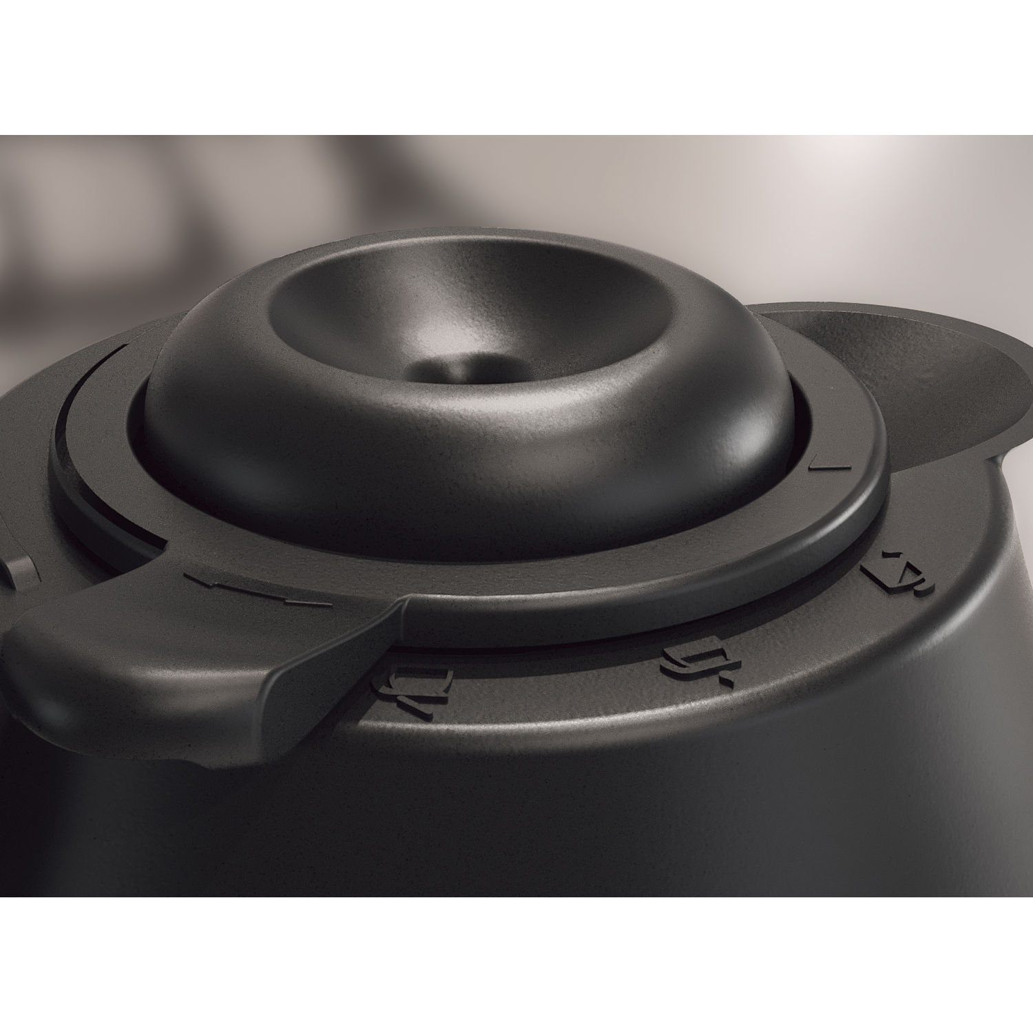 Close-up of a black plastic object. It has a central, concave feature, a dial, and a lever. Numbers are embossed on the surface.