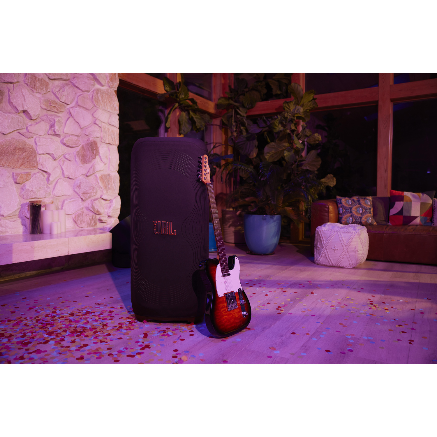 Zwarte JBL-luidspreker met gitaar, confetti op de vloer.