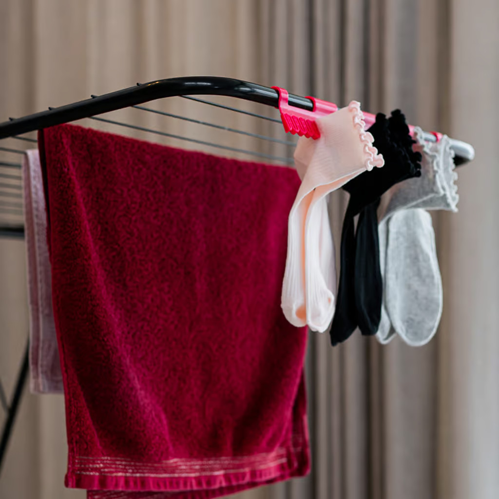 Stojak do suszenia ubrań z ręcznikami i skarpetami. Zasłona w tle.