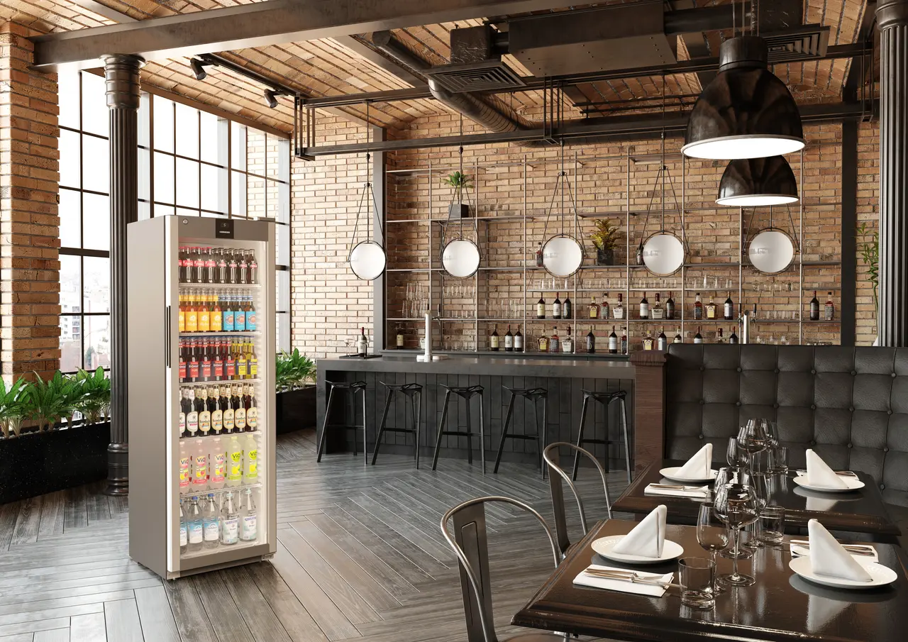 Restaurantinterieur mit Bar und Esstischen. Eine Vitrine befindet sich links.