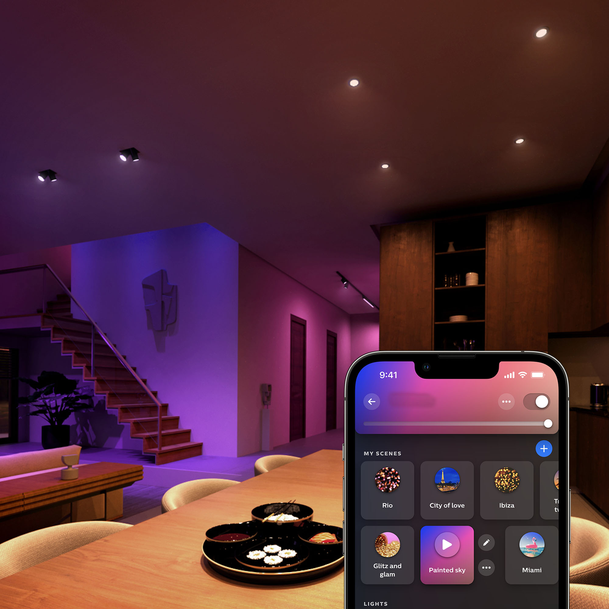 Innenraum mit intelligenten Lichtern. Ein Telefon zeigt Lichtszenen. Ein Esstisch ist gedeckt. Treppe und Schränke im Hintergrund.