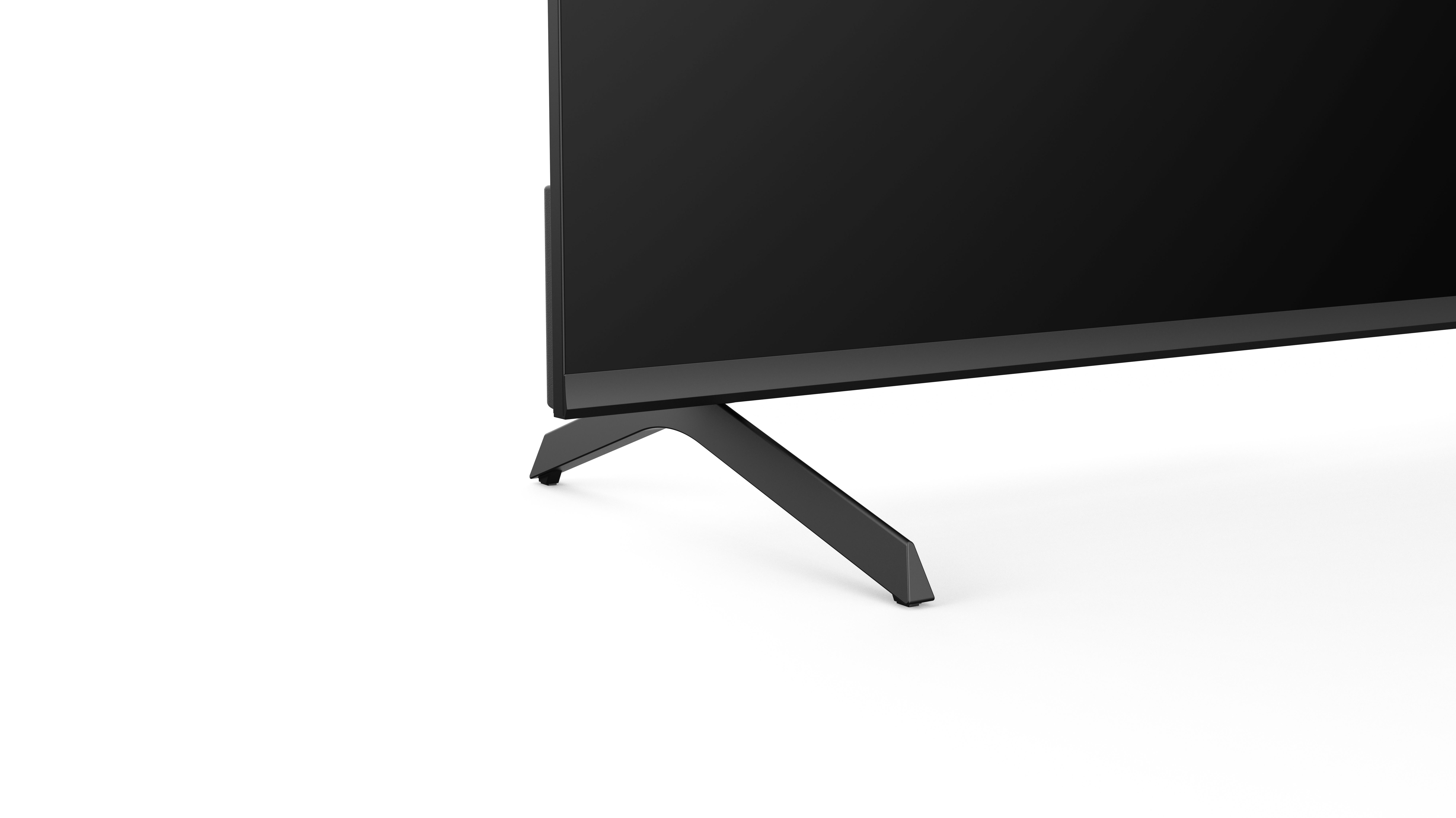 Schwarzer Fernseher mit kleinem Ständer auf weißem Hintergrund. Der Boden des Fernsehers und der Ständer sind sichtbar.