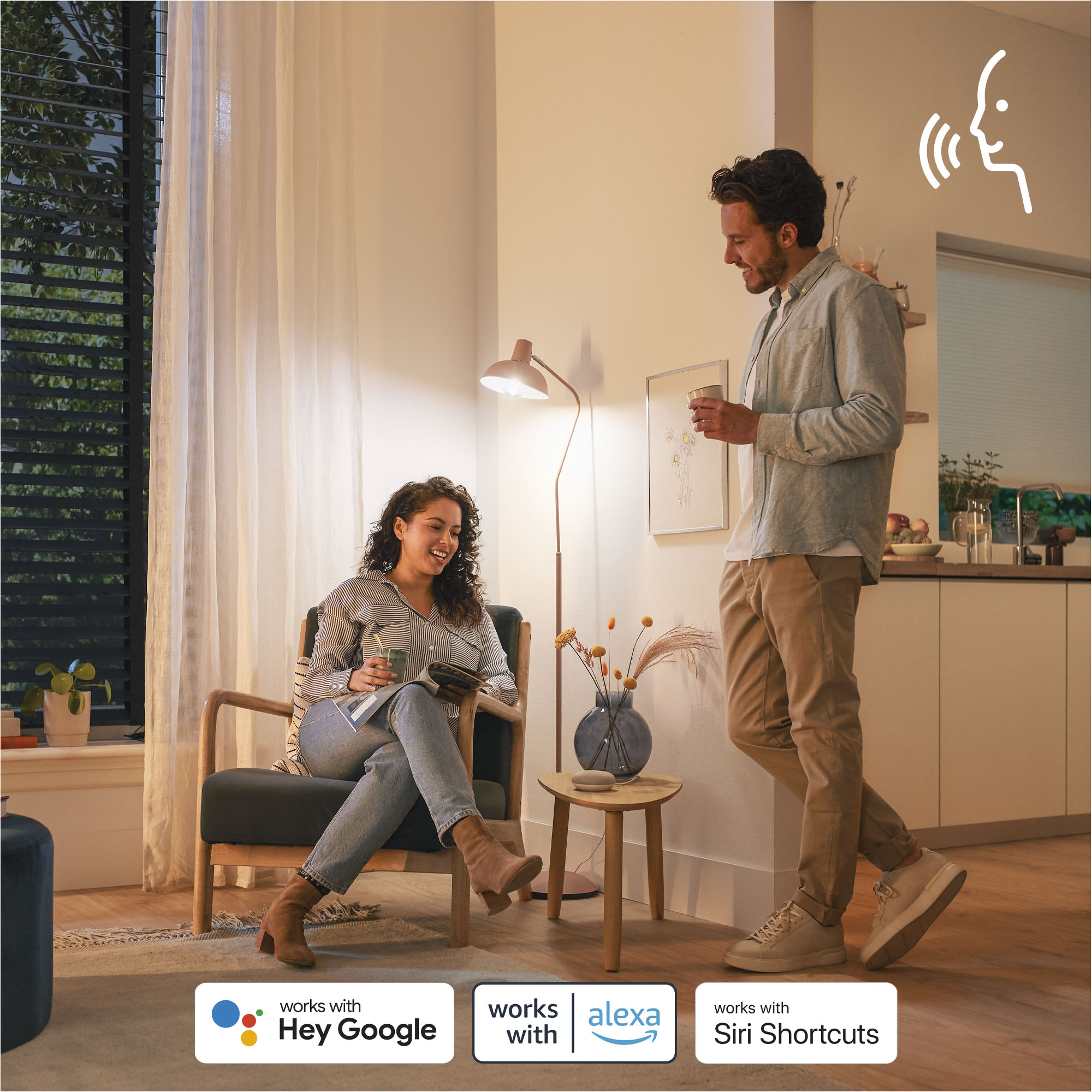 Ein Paar im Wohnzimmer, interagiert mit Smart Home Geräten. Sprachsteuerungs-Symbol.