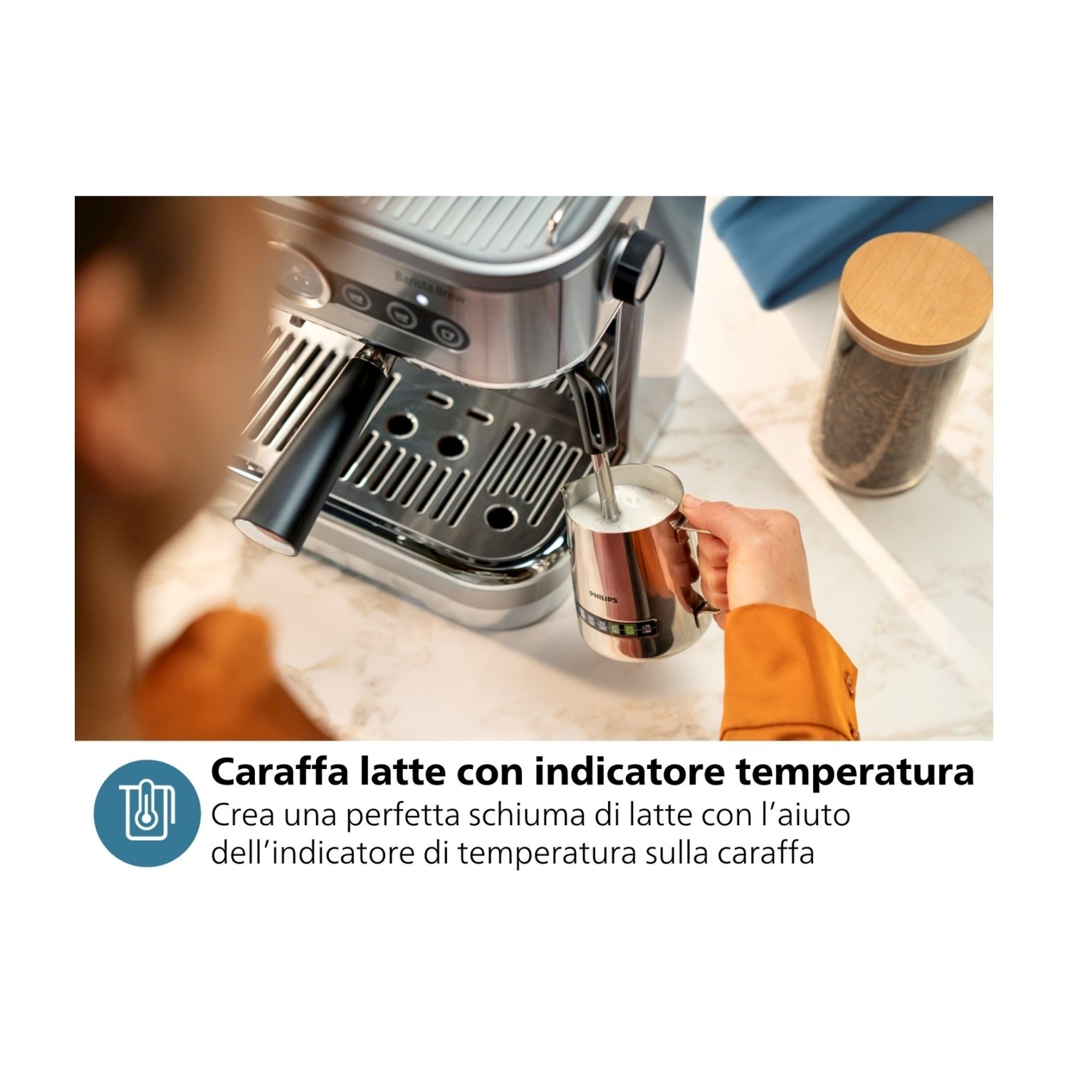 Una persona usa una macchina per l'espresso per montare il latte in una tazza di metallo.